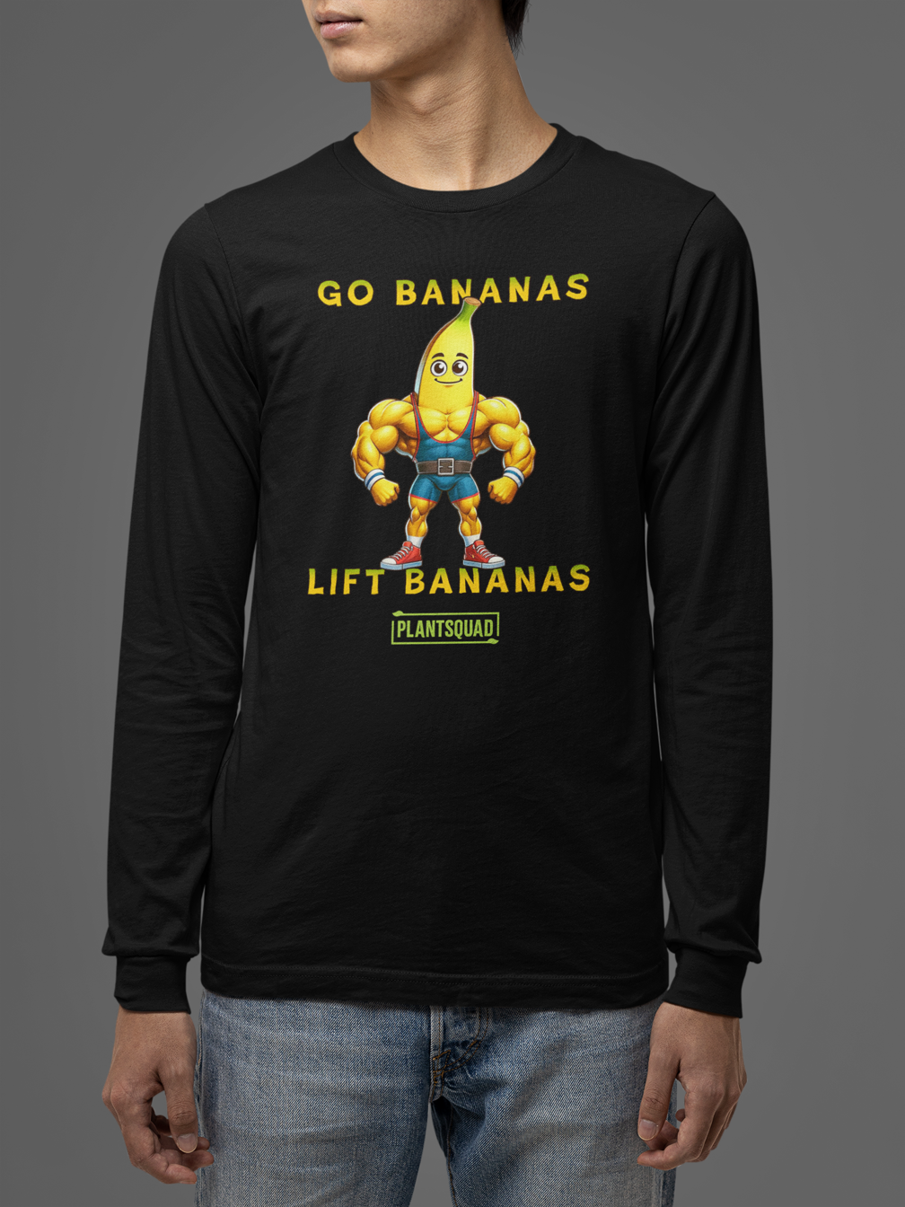The Plantsquad Banana "Go Bananas Lift Bananas" - Unisex Long Sleeve T-Shirt features a muscular cartoon banana character wearing blue shorts and white shoes. The text above the banana says, "GO BANANAS," and the text below says, "LIFT BANANAS." Perfect for fitness enthusiasts embracing a plant-based lifestyle, it sports the logo "PLANTSQUAD" at the bottom.