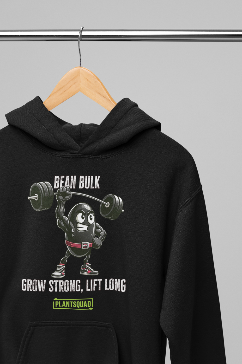 A Plantsquad Black Bean "Bean Bulk Grow Strong Lift Long" - Unisex Hoodie featuring a cartoon bean lifting a barbell with the text "BEAN BULK" above it. Below the bean, the text reads "GROW STRONG, LIFT LONG" and "PLANTSQUAD" within a green rectangle. Perfect for those embracing a vegan lifestyle, this hoodie has a front pocket and drawstrings at the neck.
