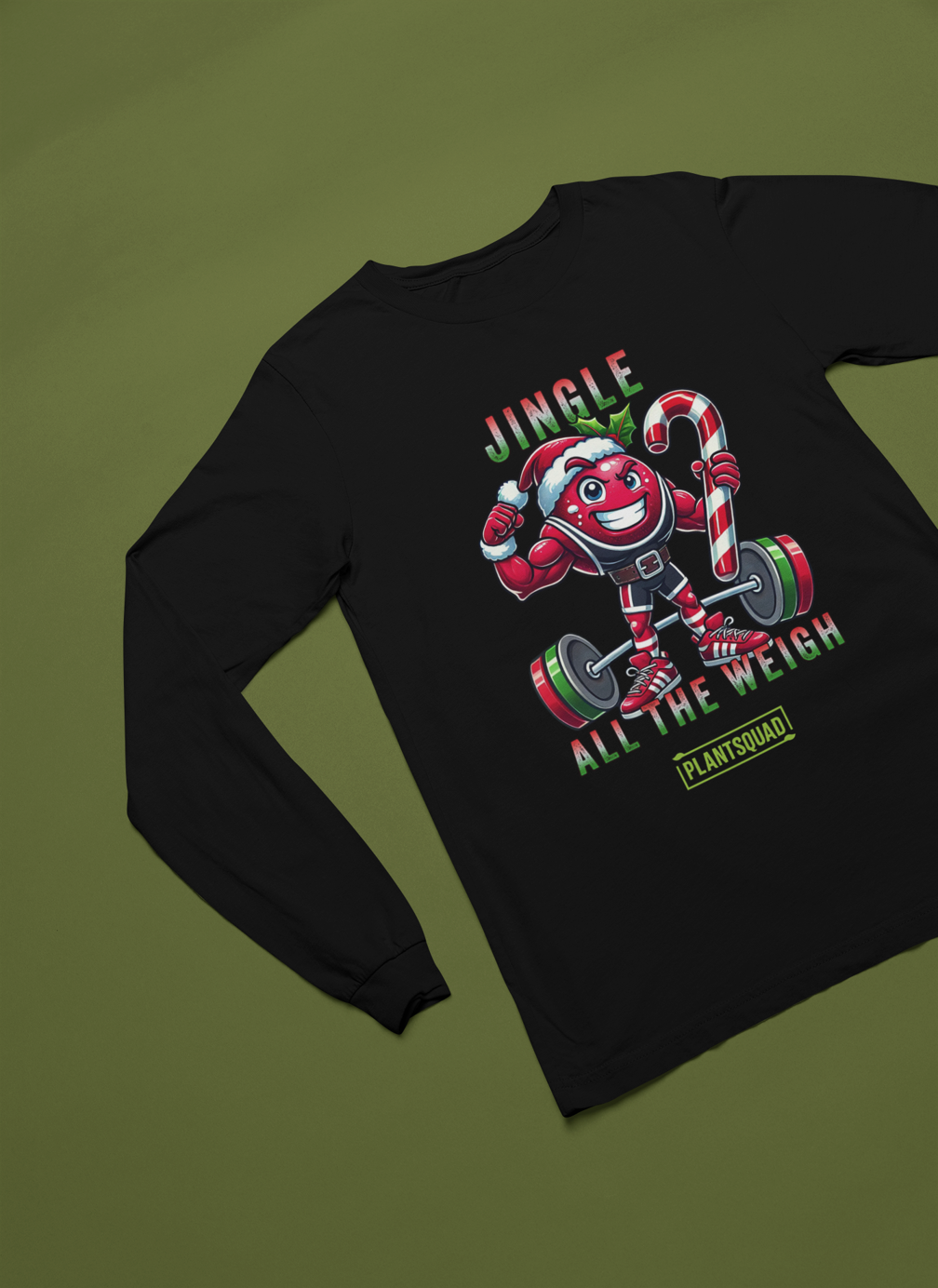 A picture of a long sleeve tee featuring a strong looking cranberry cartoon character flexing its arms holding a candy cane. A small green logo "PLANTSQUAD" appears above the character, "JINGLE ALL THE WEIGH" below. Perfect for those embracing a plant-based or vegan lifestyle that are into fitness