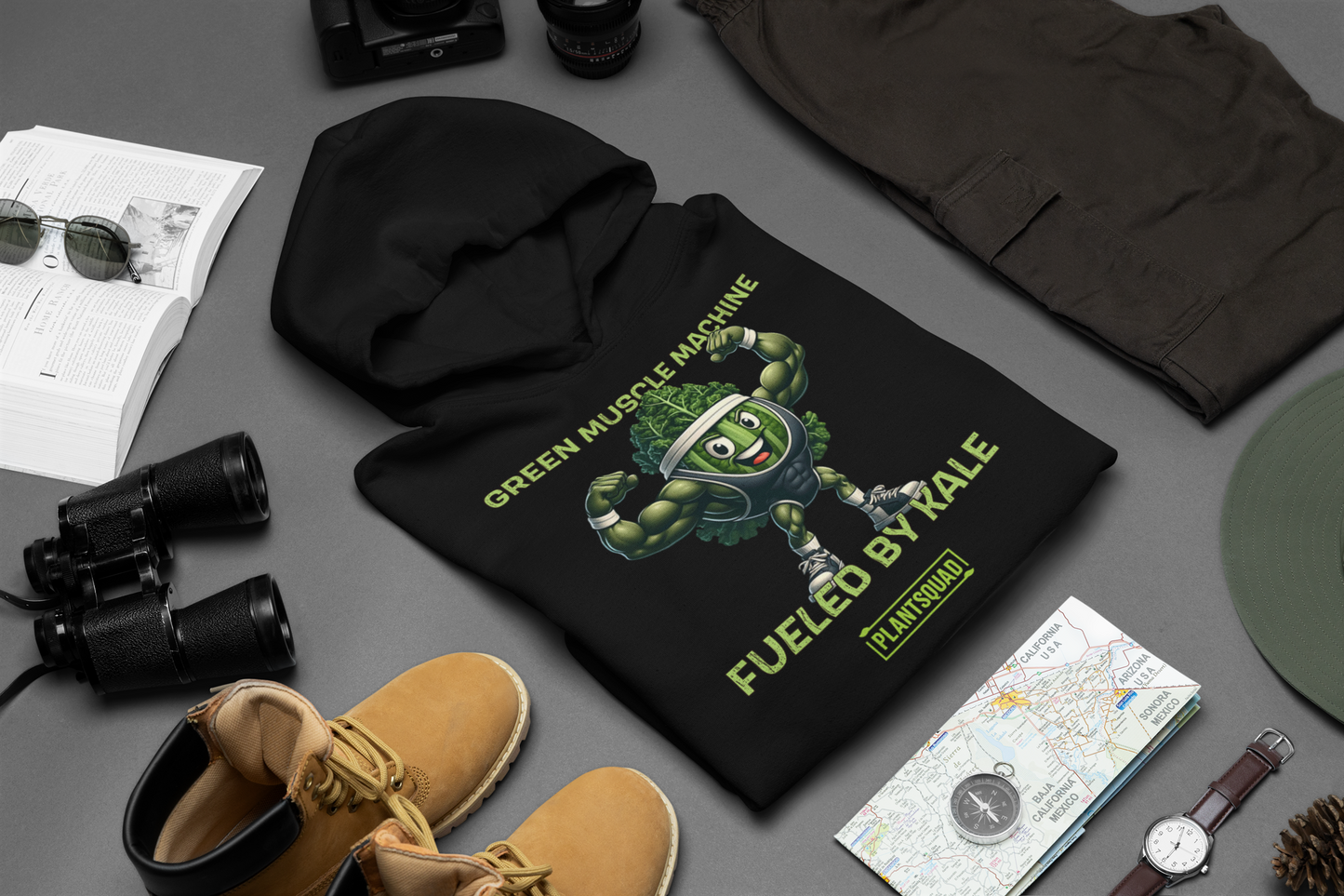 **Plantsquad Kale "Green Muscle Machine Fueled By Kale" - Unisex Hoodie** featuring an illustration of a muscular cartoon character made of kale flexing its arms. The text above reads "GREEN MUSCLE MACHINE" and below, "FUELED BY KALE." At the bottom, there's a logo with "PLANTSQUAD" written on it. Perfect for showcasing your vegan lifestyle.