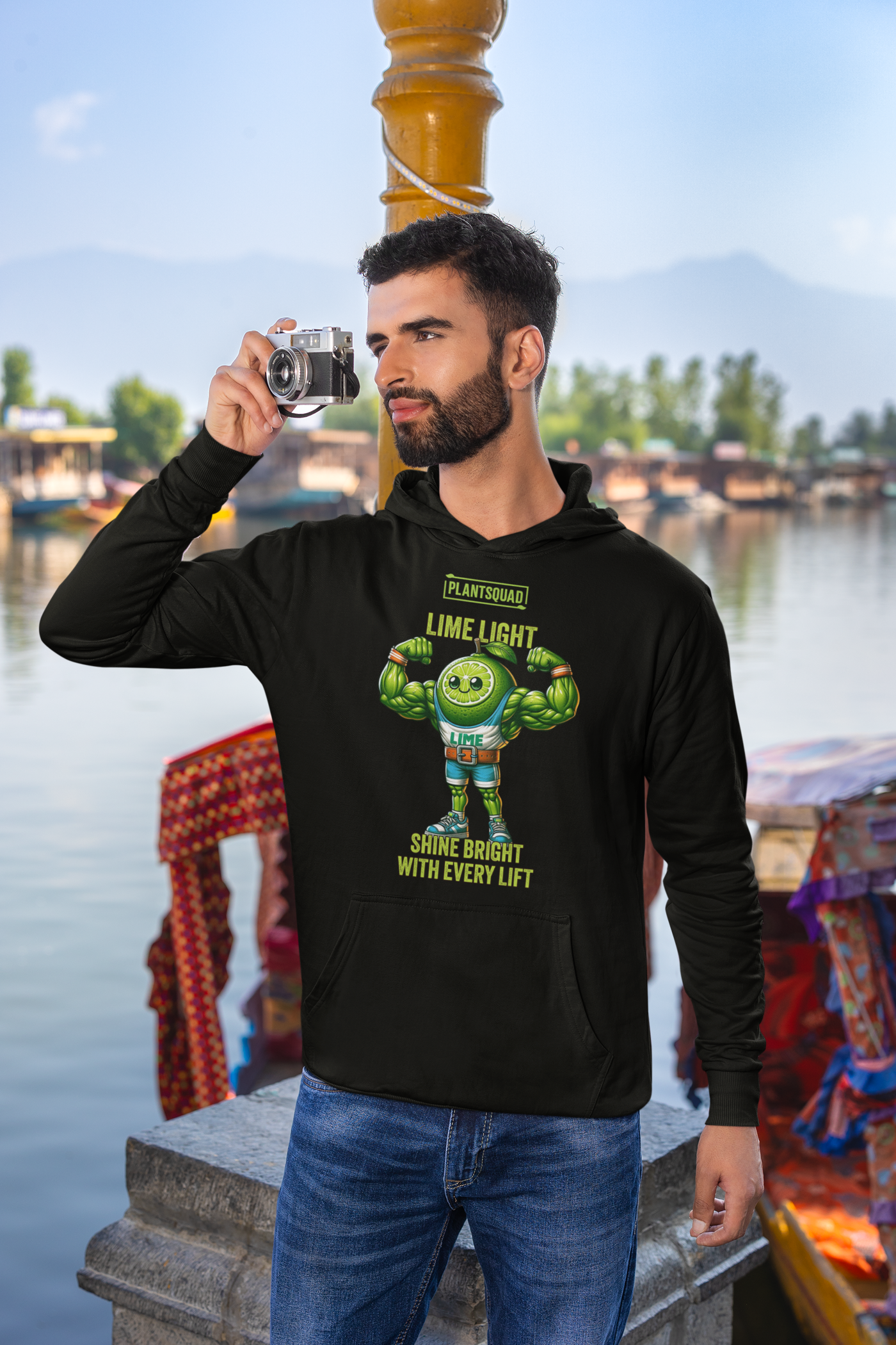 The Plantsquad Lime "Lime Light Shine Bright With Every Lift" - Unisex Hoodie features a muscular, smiling lime character flexing its biceps. The text above reads "PLANTSQUAD" and "LIME LIGHT," while below it says "SHINE BRIGHT WITH EVERY LIFT." Perfect for those embracing a plant-based lifestyle, the bright green lime stands out against the dark background.