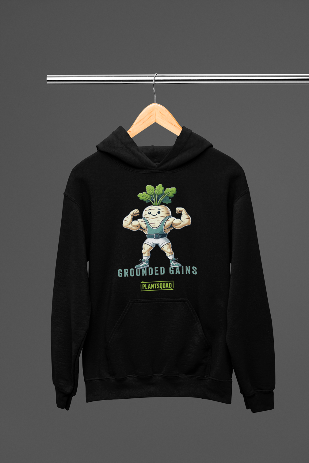 A black hoodie featuring a muscular cartoon vegetable character with green leaves on its head, flexing its arms. The text above reads "Grounded Gains" and below reads "Plantsquad." Perfect for weight lifting enthusiasts, this cozy fabric Plantsquad Parsnip "Grounded Gains" - Unisex Hoodie celebrates the vegan lifestyle in style.