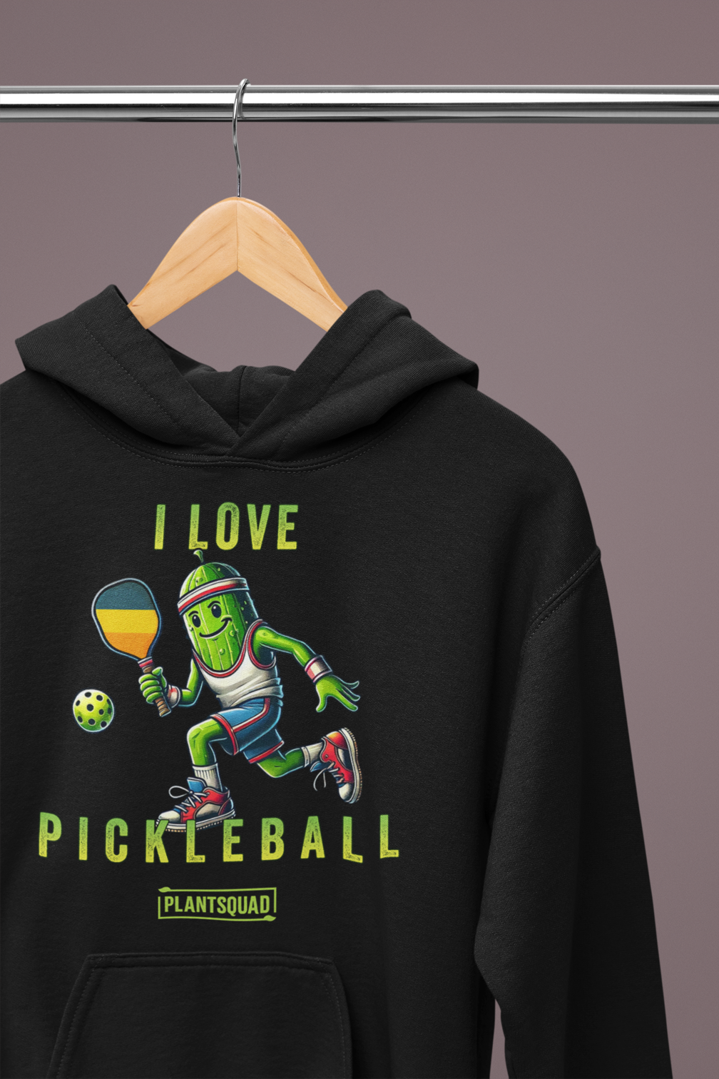 A hoodie featuring a pickle playing pickleball. There is a caption listed as "I Love Pickleball", with a small green logo "PLANTSQUAD" underneath. Perfect for those who love pickleball.