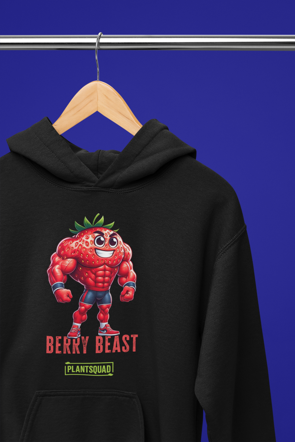 A Plantsquad Strawberry "Berry Beast" - Unisex Hoodie featuring a cartoonish, muscular strawberry character wearing red shorts and gloves. The character stands confidently with the text "Berry Beast" above and "Plant Squad" below—perfect for those embracing the vegan lifestyle.