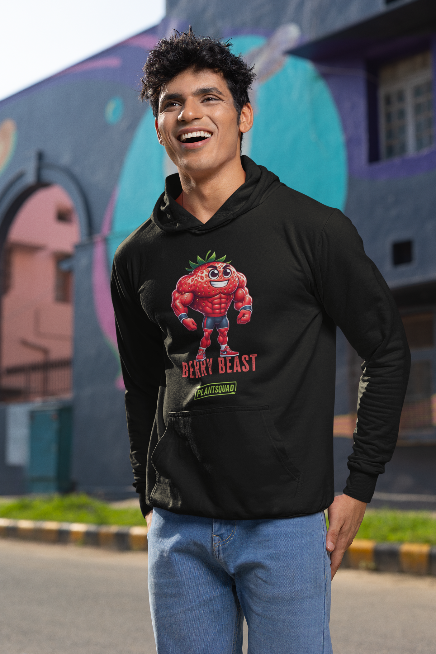 A Plantsquad Strawberry "Berry Beast" - Unisex Hoodie featuring a cartoonish, muscular strawberry character wearing red shorts and gloves. The character stands confidently with the text "Berry Beast" above and "Plant Squad" below—perfect for those embracing the vegan lifestyle.