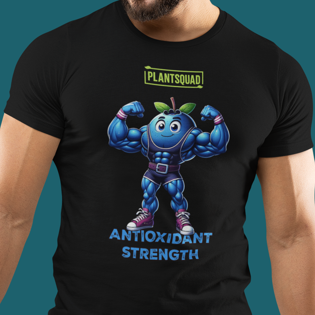 Close-up of a black T-shirt featuring a cartoon muscular blueberry character wearing sneakers and a belt, flexing its arms. The shirt has the text "PLANTSQUAD" in green above the character and "ANTIOXIDANT STRENGTH" in blue below it.