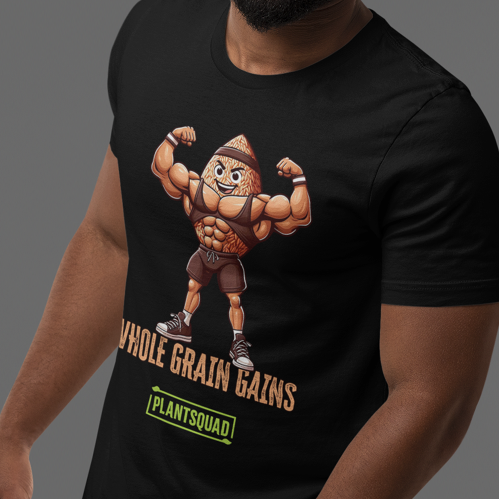 A person is wearing a black T-shirt featuring an illustrated character of a muscular grain flexing its biceps. The text on the shirt reads "WHOLE GRAIN GAINS" and "PLANTSQUAD." The background is a plain gray.