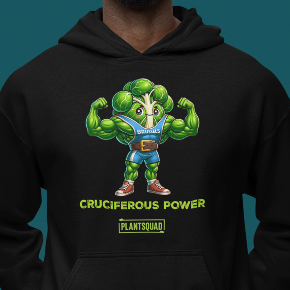 A person wearing a black hoodie with a graphic of a muscular cartoon Brussels sprout in a blue outfit flexing its arms. The text below the character reads "CRUCIFEROUS POWER" in bright green, followed by "PLANTSQUAD" underneath.