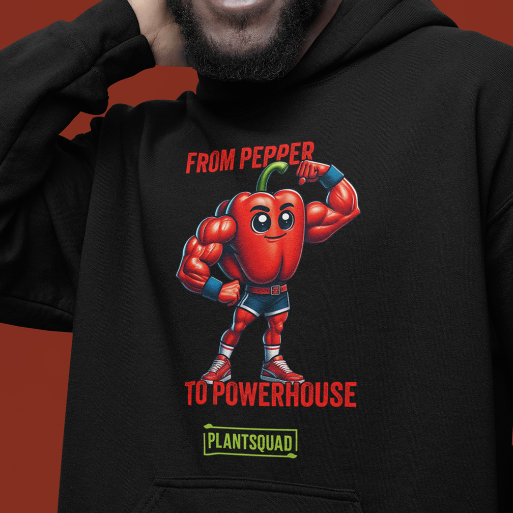 A person is wearing a black hoodie featuring a muscular cartoon red bell pepper with a green stem and flexing arms. The text reads, "FROM PEPPER TO POWERHOUSE" and "PLANTSQUAD." The background color is deep red.