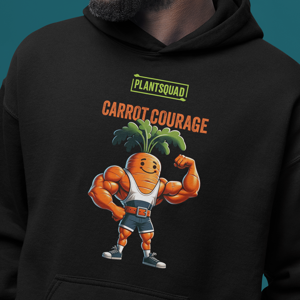 A person wears a black hoodie featuring a muscular cartoon carrot flexing one arm. The carrot character is dressed in a white tank top, black shorts, and sneakers. Above the character, the text reads "PLANTSQUAD" and below it, "CARROT COURAGE.