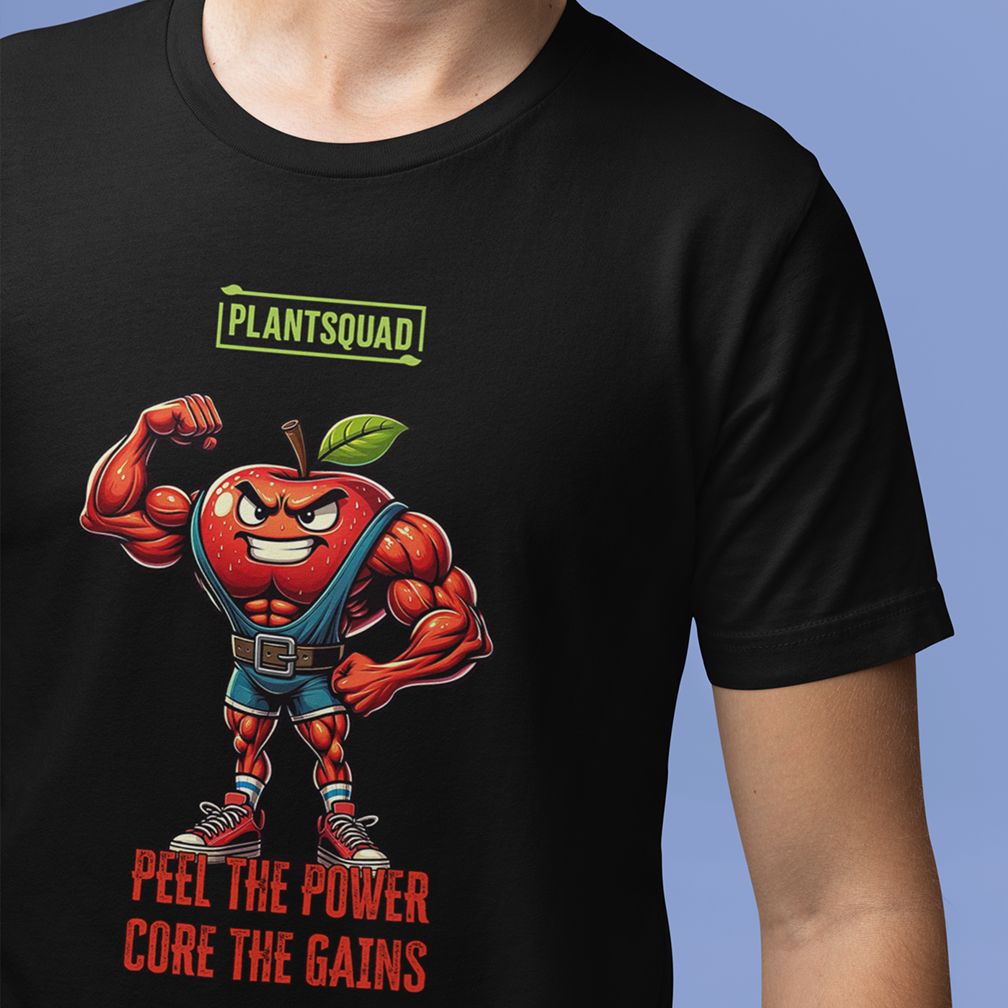 A person wearing a black long-sleeve shirt with a cartoon image of a muscular apple flexing its arms. The text above the apple reads "PLANTSQUAD" and below it reads "PEEL THE POWER, CORE THE GAINS". The person is standing against a red background.