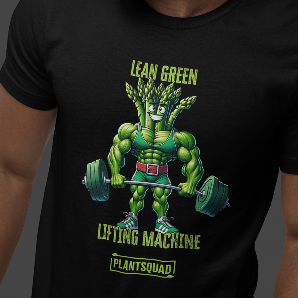 A person wears a black T-shirt featuring a muscular cartoon asparagus character lifting a barbell. The shirt has green text that reads "LEAN GREEN LIFTING MACHINE" and "PLANTSQUAD" beneath the character.