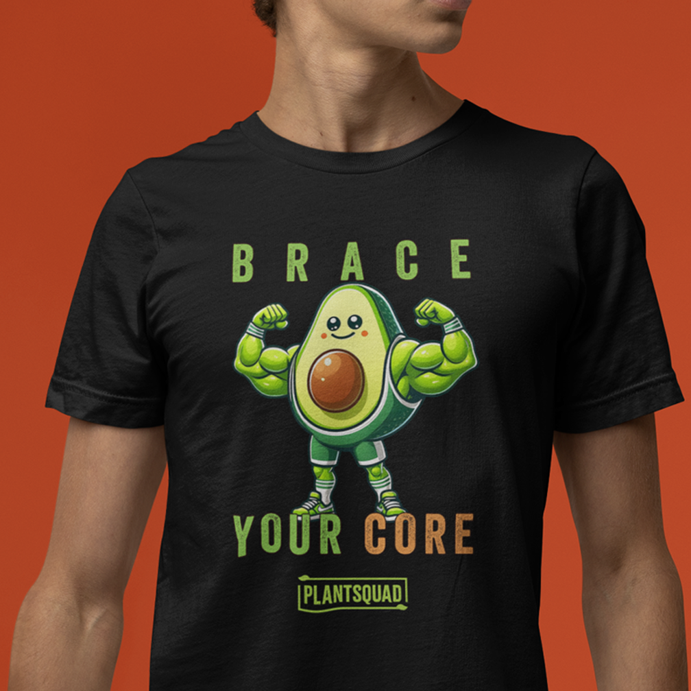 A T-shirt is displayed on a hanger, which is held up by a frame against a gray background. The black T-shirt features an illustration of a muscular avocado with the text "BRACE YOUR CORE" and "PLANT SQUAD" printed below it in green and orange.