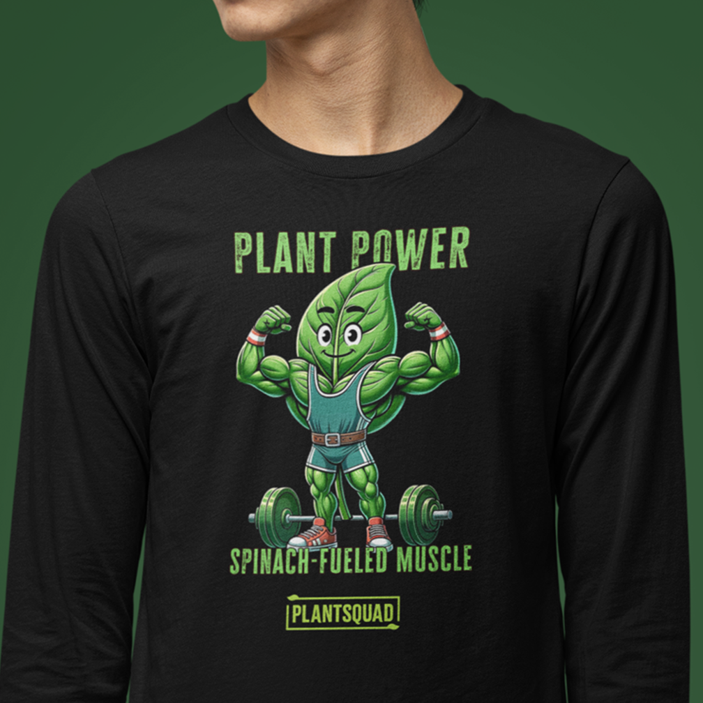 A person is wearing a black long-sleeve shirt featuring a muscular cartoon spinach leaf character lifting a barbell. The text above and below the character reads "PLANT POWER" and "SPINACH-FUELED MUSCLE," with "PLANTSQUAD" at the bottom.