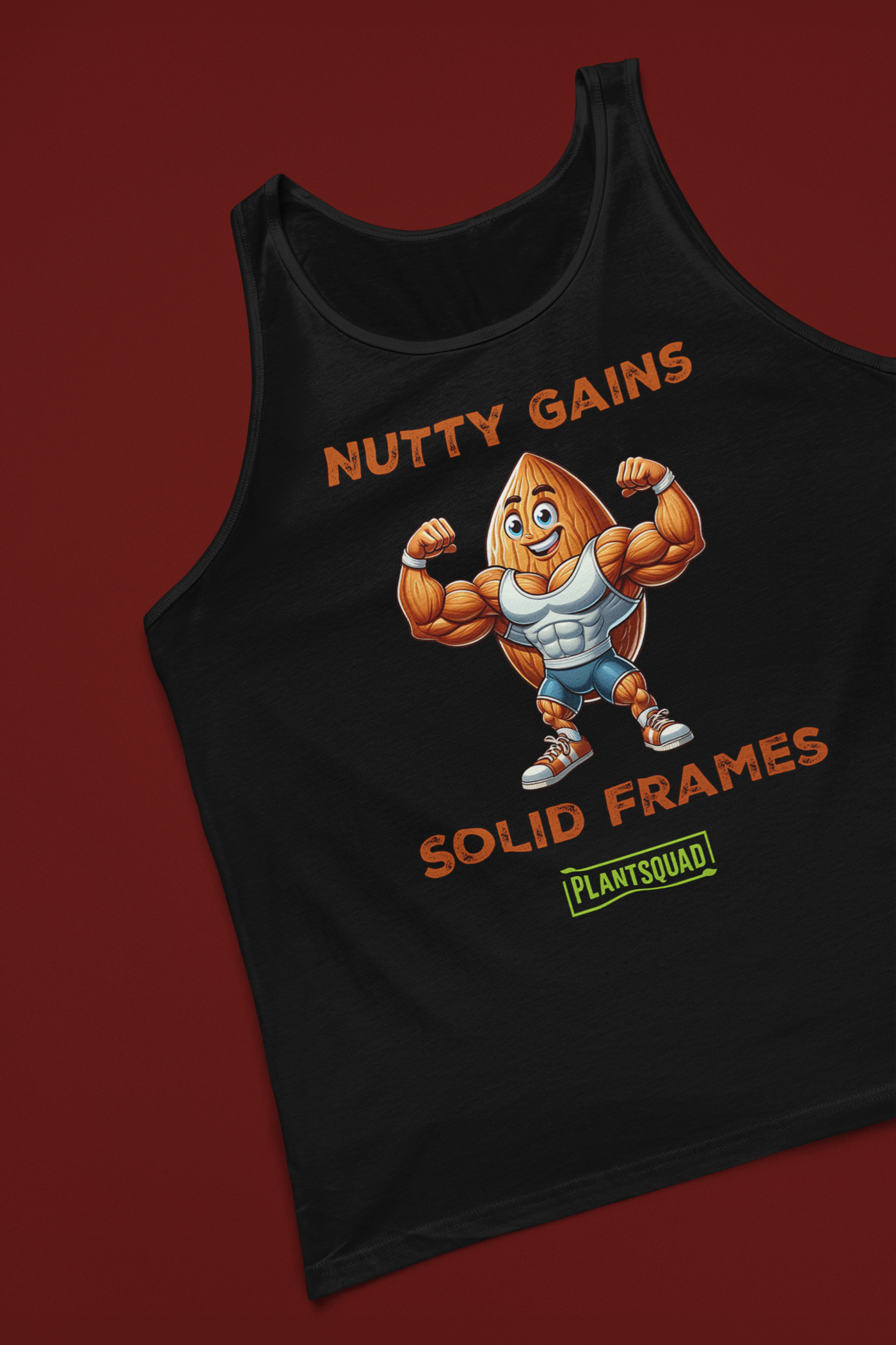 This Plantsquad Almond "Nutty Gains Solid Frames" - Unisex Tank Top features a buff, anthropomorphic almond flexing its muscles. Above it, in bold orange text, reads "NUTTY GAINS." Below, it says "SOLID FRAMES." At the bottom is a green rectangular logo with the text "PLANTSQUAD," perfect for showcasing your vegan lifestyle.