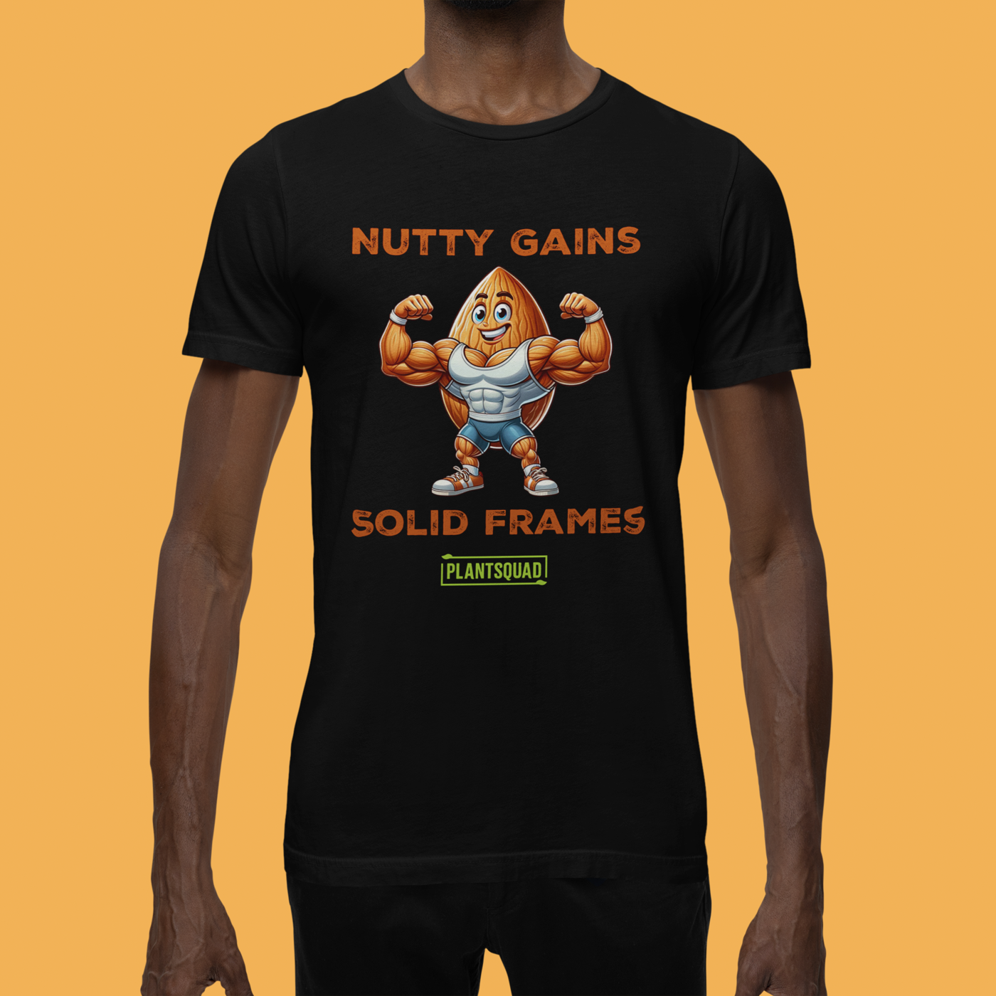 A black T-shirt features a muscular cartoon peanut character flexing its arms. Above the character, text reads "Nutty Gains," and below, "Solid Frames." The Plantsquad Almond "Nutty Gains Solid Frames" - Unisex T-Shirt logo appears at the bottom in green.