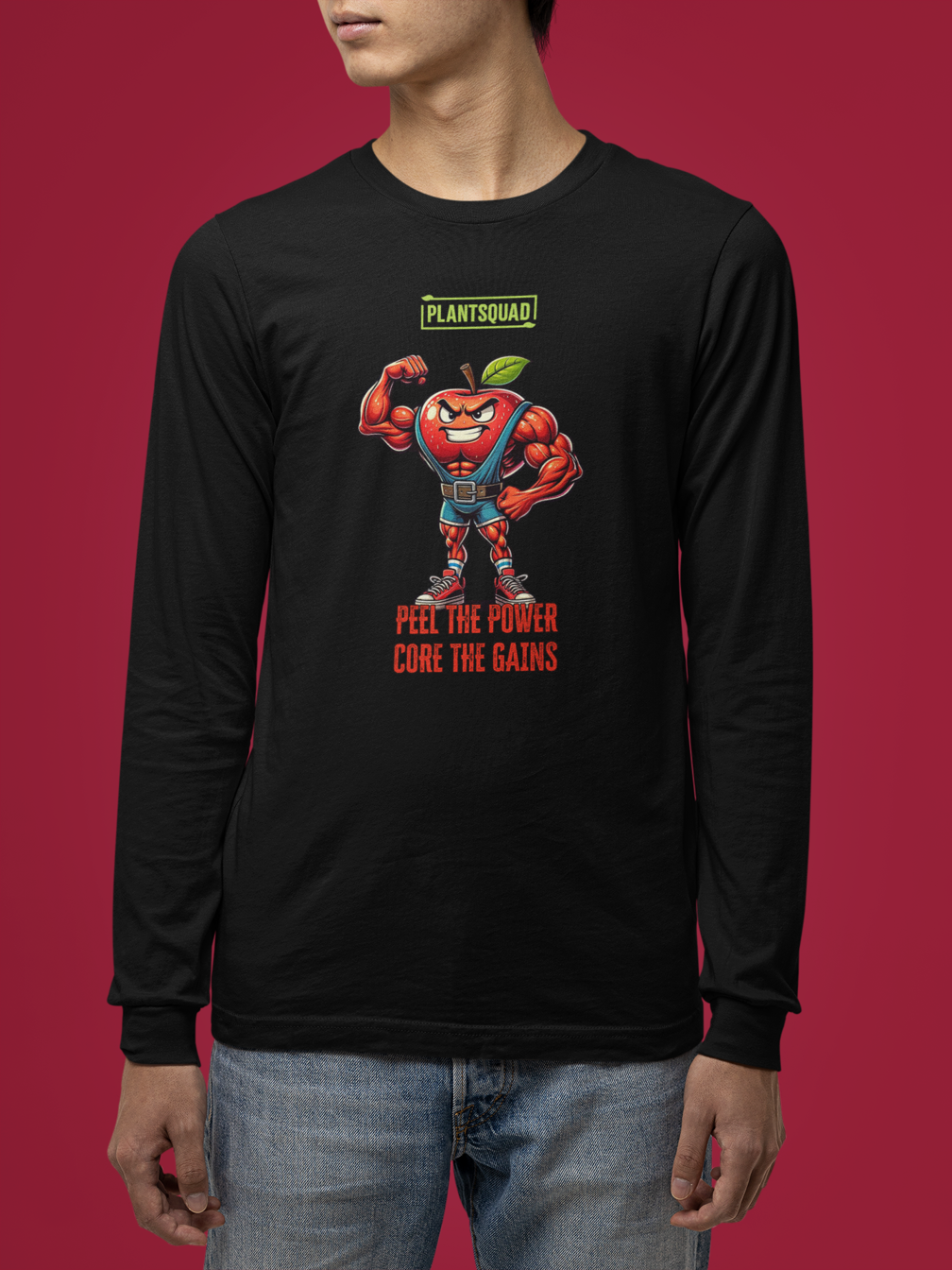 Plantsquad Apple "Peel The Power Core The Gains" - Unisex Long Sleeve T-Shirt featuring a muscly apple design, flexing with a confident expression, wearing blue suspenders and red boots. The text "PLANTSQUAD" hovers above the apple, while below reads "PEEL THE POWER CORE THE GAINS" in bold red text—perfect for promoting a plant-based lifestyle.