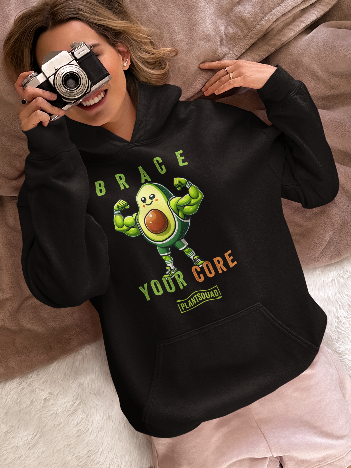 Plantsquad Avocado "Brace Your Core" - Unisex Hoodie featuring a muscular avocado cartoon flexing its arms. Text above the avocado reads "Brace," and below it says "Your Core" in green and orange letters. The bottom text reads "PLANT SQUAD" in a green box. Embrace the vegan lifestyle with this cozy fabric, perfect for weight lifting and more.