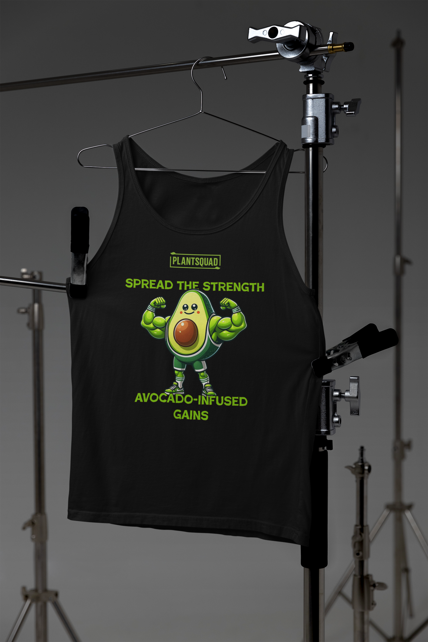 A Plantsquad Avocado "Spread The Strength Avocado-Infused Gains" - Unisex Tank Top featuring a muscly avocado cartoon flexing its arms. Above the avocado, it reads "PLANTSQUAD," while below it says, "SPREAD THE STRENGTH AVOCADO-INFUSED GAINS" in yellow-green letters. Perfect for embracing a plant-based lifestyle and vegan gym wear enthusiasts.