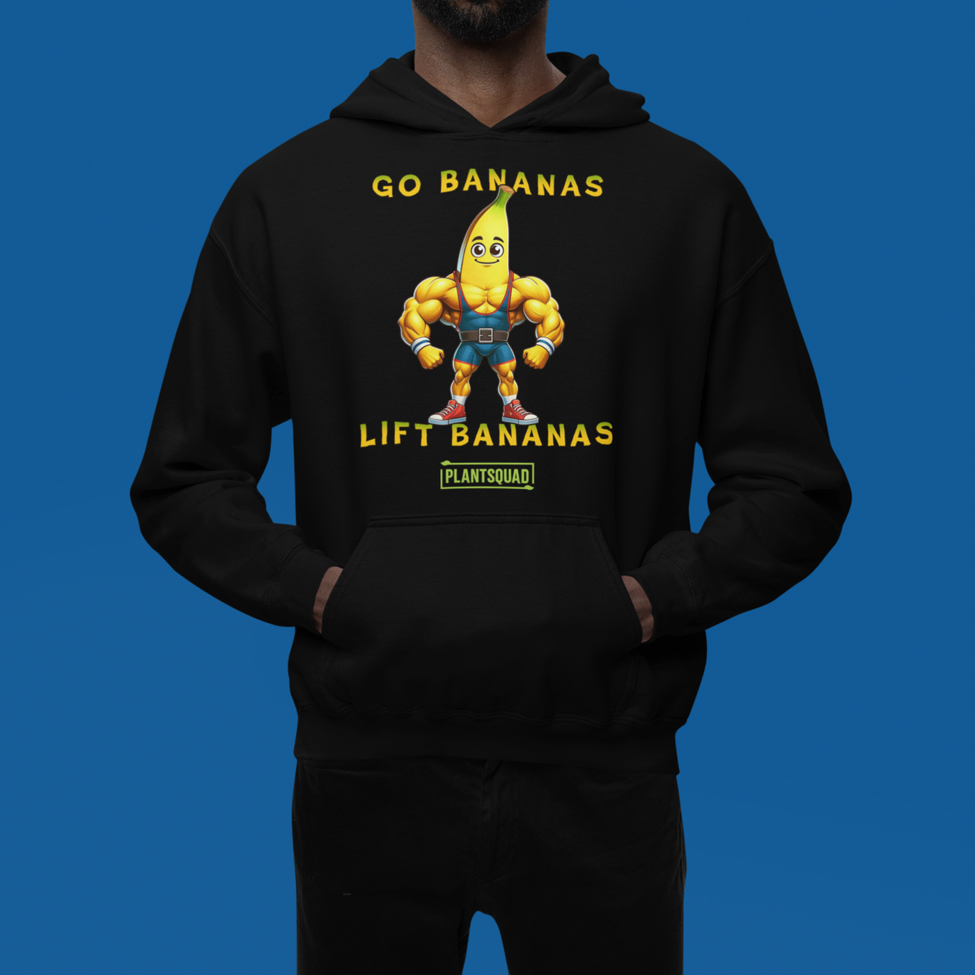 A black vegan hoodie featuring a muscular cartoon banana character flexing its arms. The text above the character reads "GO BANANAS" and below the character reads "LIFT BANANAS." There is a small "PLANTSQUAD" logo beneath the character, ideal for those embracing a plant-based lifestyle and weight lifting apparel. The product name is Plantsquad Banana "Go Bananas Lift Bananas" - Unisex Hoodie.