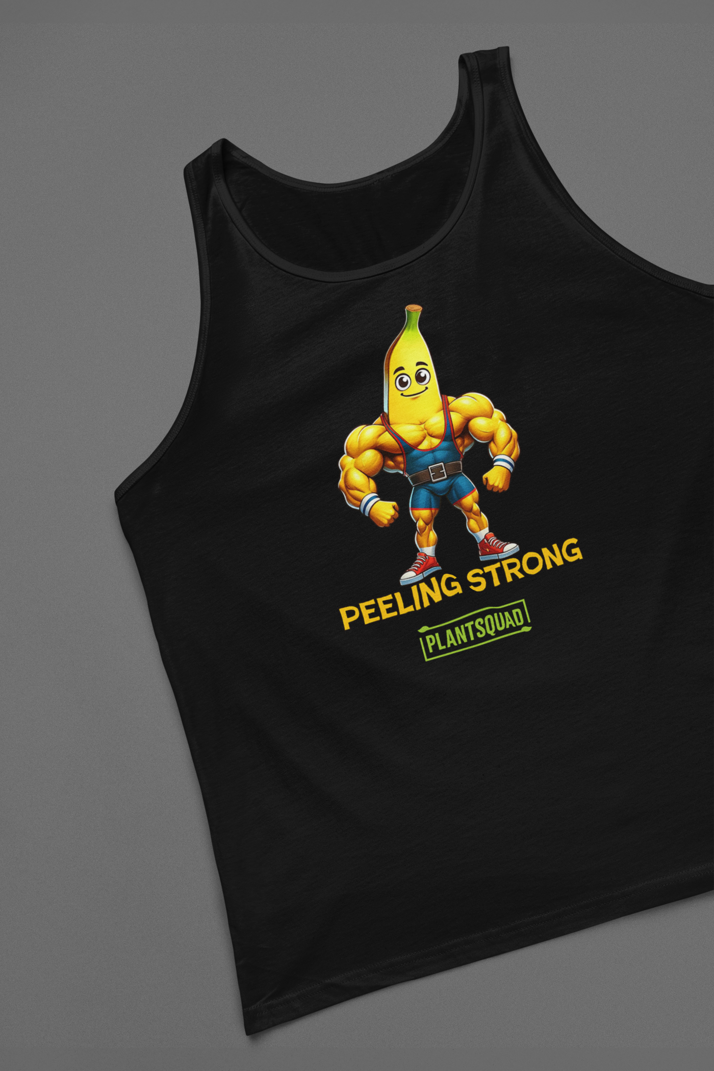 A Plantsquad Banana "Peeling Strong" - Unisex Tank Top features a muscly banana cartoon with a muscular human body, wearing gym clothes and flexing its arms. The text "PEELING STRONG" is written below the image, with "PLANTSQUAD" displayed underneath in a green rectangle, perfect for those embracing a plant-based lifestyle and vegan gym wear.