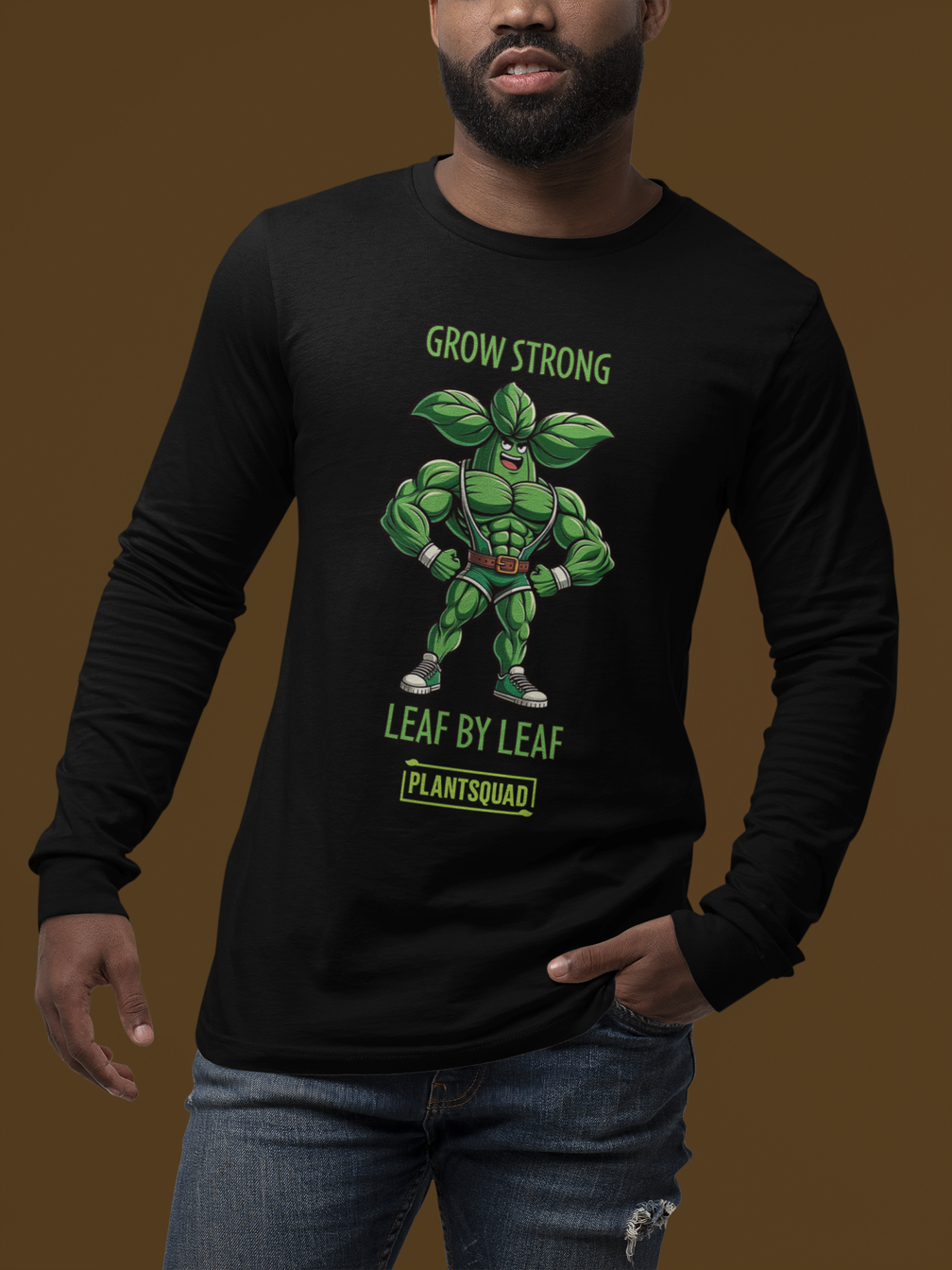 A black long-sleeve t-shirt featuring an illustration of a muscular, anthropomorphic green leaf superhero. Above the image is the text "GROW STRONG," and below it reads "LEAF BY LEAF." The bottom features the word "PLANTSQUAD," perfect for those embracing a vegan lifestyle or seeking plant-based clothing. Introducing the Plantsquad Basil "Grow Strong Leaf By Leaf" - Unisex Long Sleeve T-Shirt.