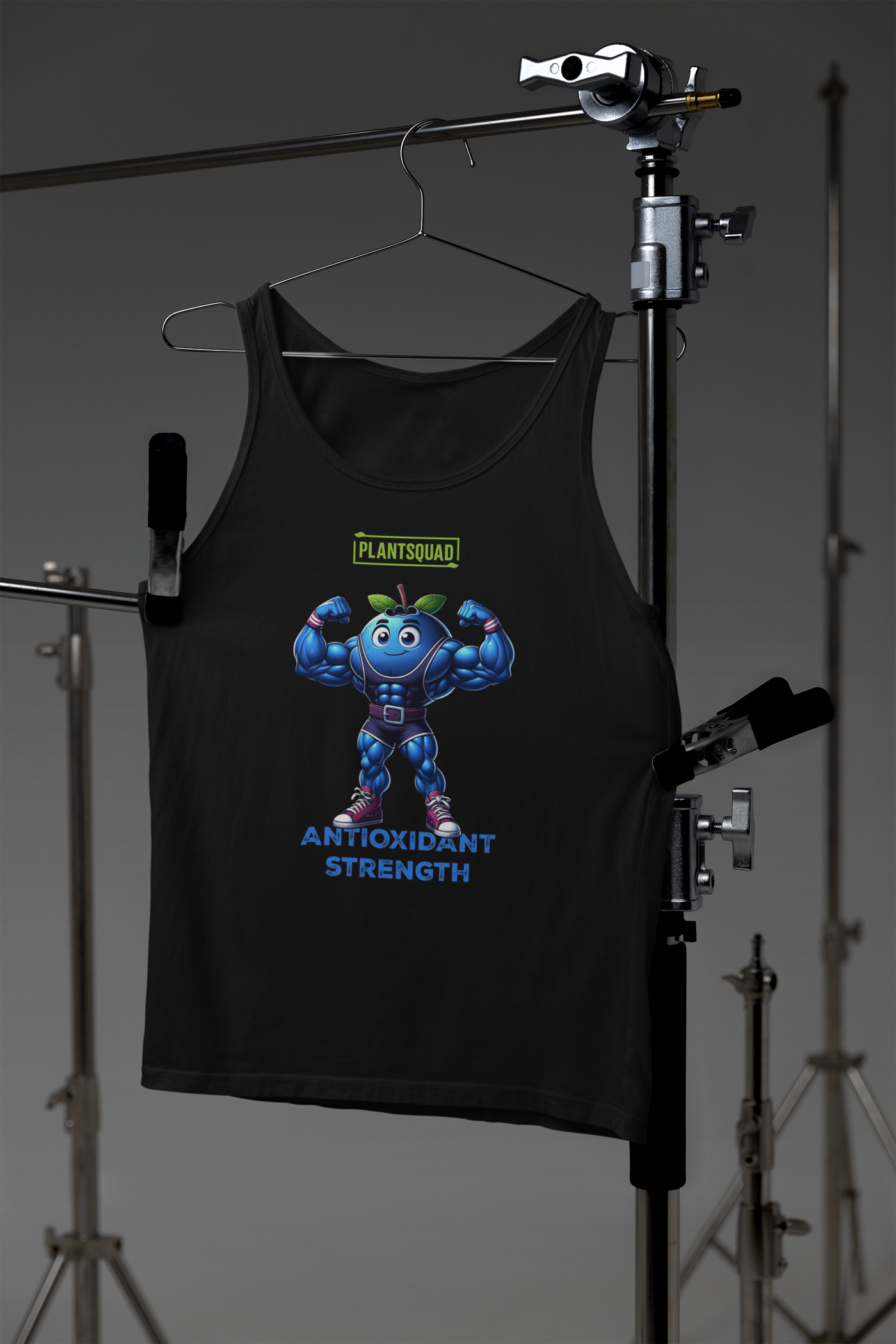 A black **Plantsquad Blueberry "Antioxidant Strength" - Unisex Tank Top** featuring a muscly blueberry cartoon flexing its arms. Above the blueberry, the word "Plantsquad" is displayed in a green box. Below the character, the words "Antioxidant Strength" are written in blue. Perfect for embracing a vegan lifestyle with premium breathable fabric for ultimate comfort.