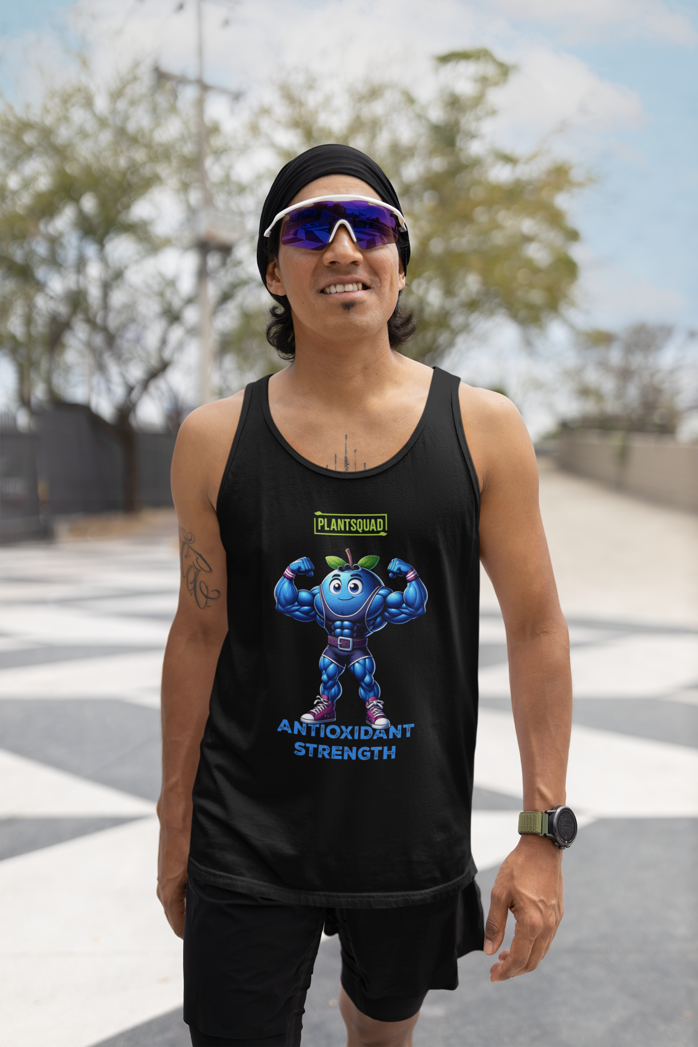 A black **Plantsquad Blueberry "Antioxidant Strength" - Unisex Tank Top** featuring a muscly blueberry cartoon flexing its arms. Above the blueberry, the word "Plantsquad" is displayed in a green box. Below the character, the words "Antioxidant Strength" are written in blue. Perfect for embracing a vegan lifestyle with premium breathable fabric for ultimate comfort.