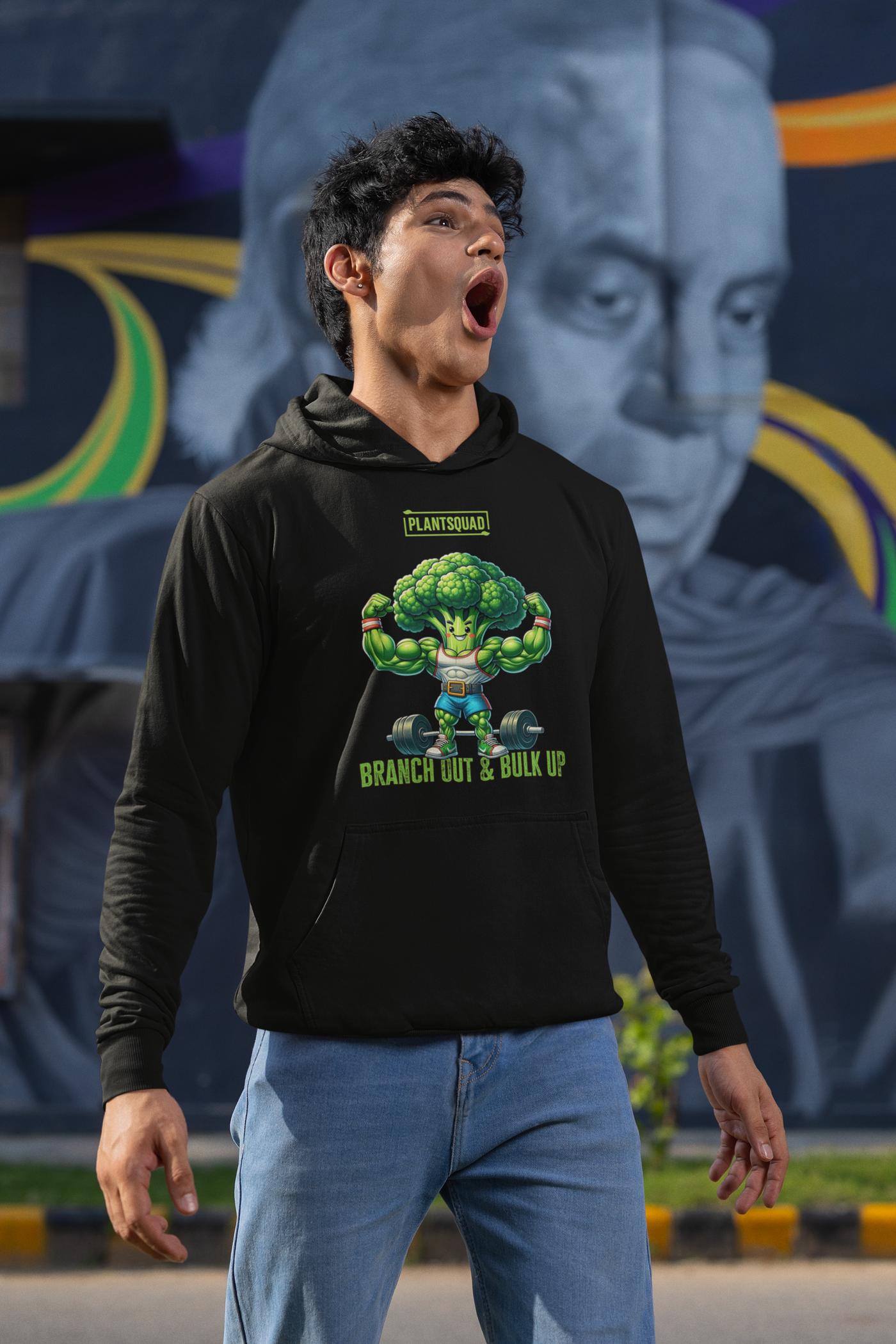 A Plantsquad Broccoli "Branch Out & Bulk Up" - Unisex Hoodie made from cozy fabric features an illustration of a muscular, anthropomorphic broccoli lifting dumbbells. The text above reads "PLANTSQUAD" and below reads "BRANCH OUT & BULK UP!" Perfect for those embracing a vegan lifestyle, the hoodie has a front pocket and a drawstring hood.