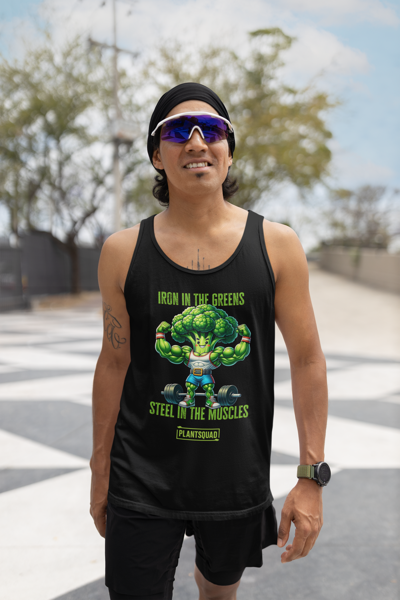 The Plantsquad Broccoli "Iron In The Greens Steel In The Muscles" - Unisex Tank Top features an illustration of a muscular broccoli character lifting weights. The text above reads "Iron in the Greens" and below reads "Steel in the Muscles" with "Plantsquad" at the bottom—perfect for gym enthusiasts embracing a plant-based lifestyle.