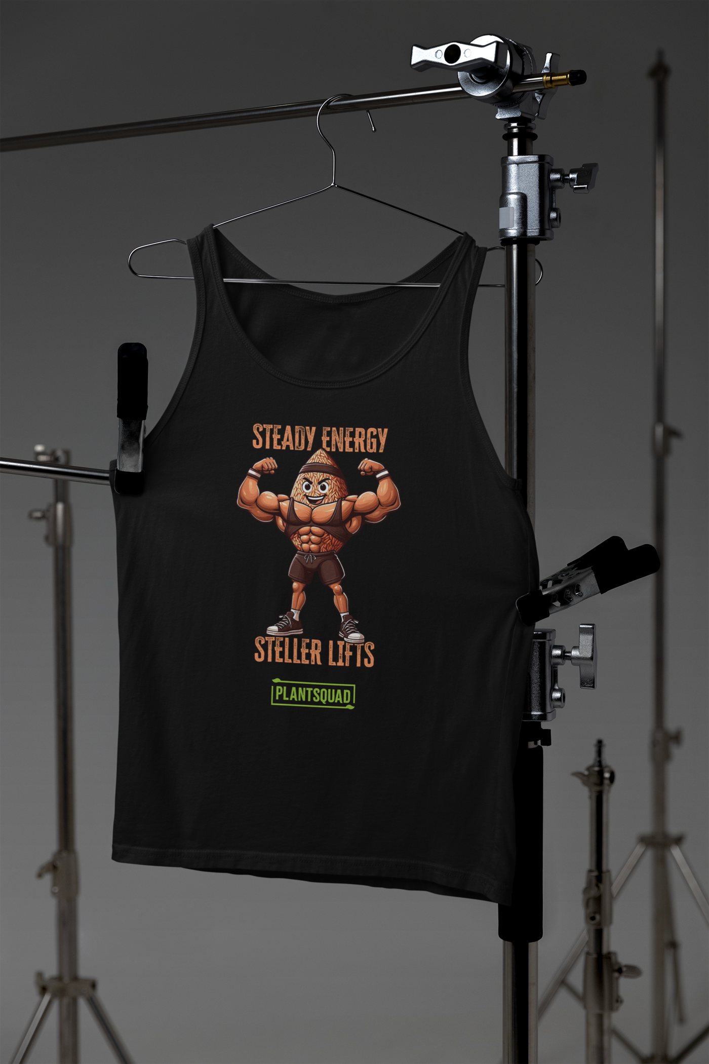 A Plantsquad Brown Rice "Steady Energy Steller Lifts" - Unisex Tank Top featuring a cartoon nut character flexing muscles. Above the character, the text reads "STEADY ENERGY." Below, it says "STELLER LIFTS." At the bottom, there's a green rectangle with the word "PLANTSQUAD," perfect for a plant-based lifestyle.