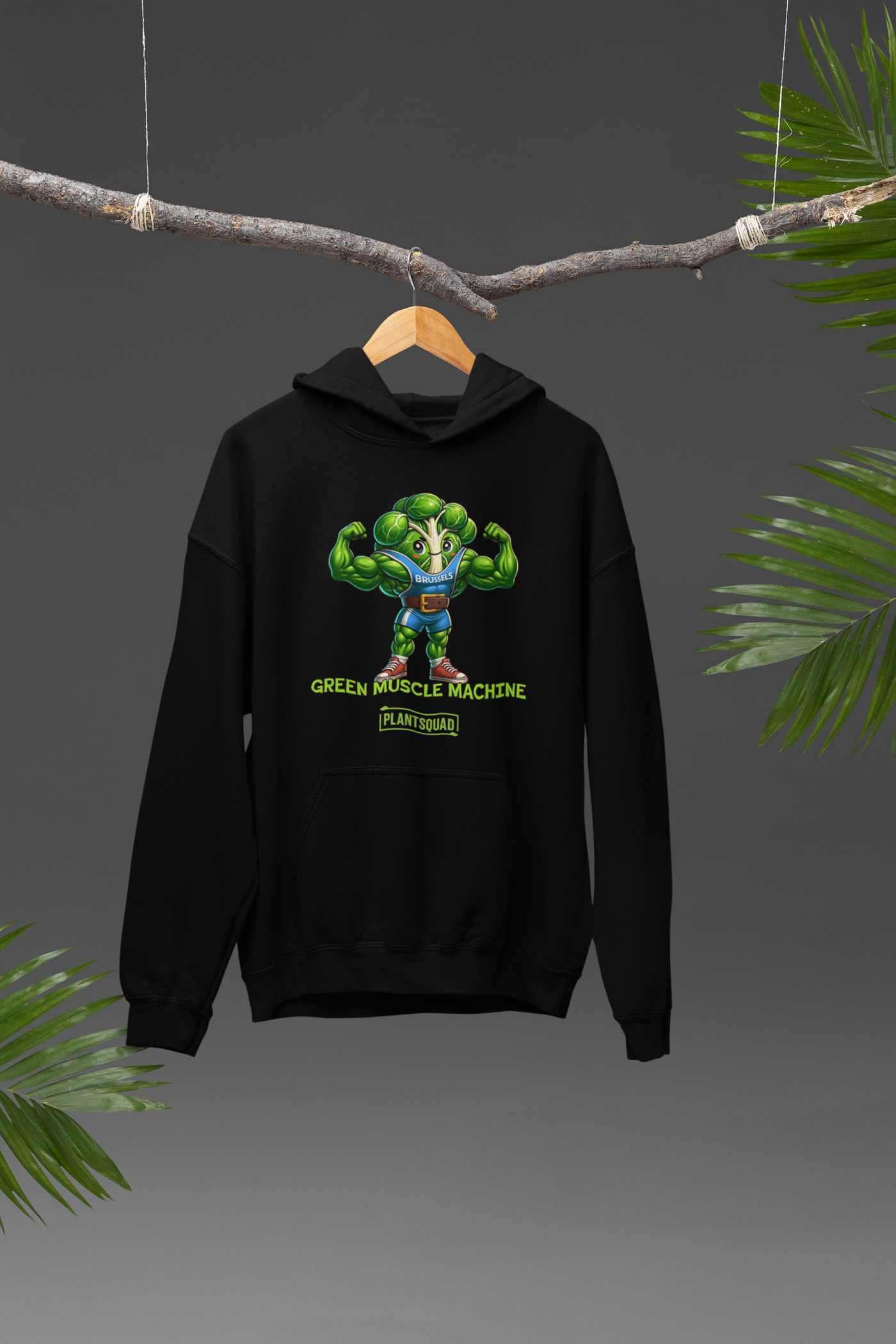 A black **Plantsquad Brussel Sprout "Green Muscle Machine" - Unisex Hoodie** featuring a muscular, anthropomorphic broccoli character flexing its arms. Text below the character reads "GREEN MUSCLE MACHINE" with "PLANTSQUAD" underneath—perfect for those embracing a plant-based lifestyle and seeking stylish vegan gym wear.