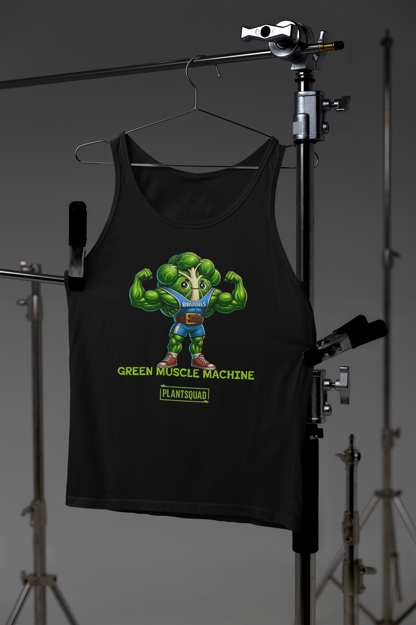 The Plantsquad Brussel Sprout "Green Muscle Machine" - Unisex Tank Top features a muscular, anthropomorphic Brussels sprout character flexing its arms. The character wears a blue shirt with "Brussels" on it. Below, the text reads "GREEN MUSCLE MACHINE" and "PLANTSQUAD." Perfect for gym enthusiasts who embrace the vegan lifestyle.