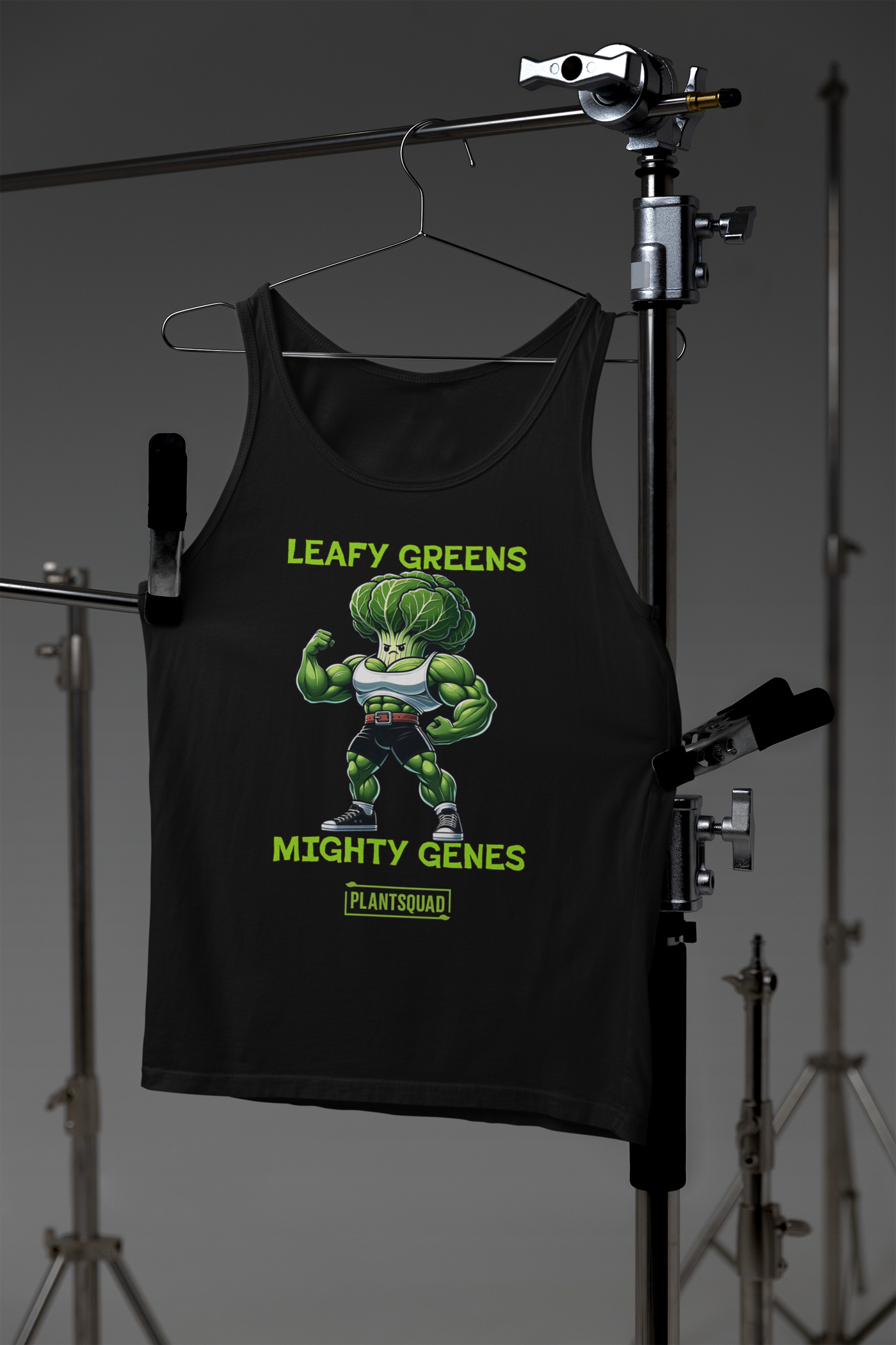 A Plantsquad Cabbage "Leafy Greens Mighty Genes" - Unisex Tank Top featuring a muscular cartoon broccoli character flexing its arms. The text above reads "LEAFY GREENS" and below reads "MIGHTY GENES" with "PLANTSQUAD" in all caps beneath the illustration—a perfect fit for gym enthusiasts embracing a plant-based lifestyle.