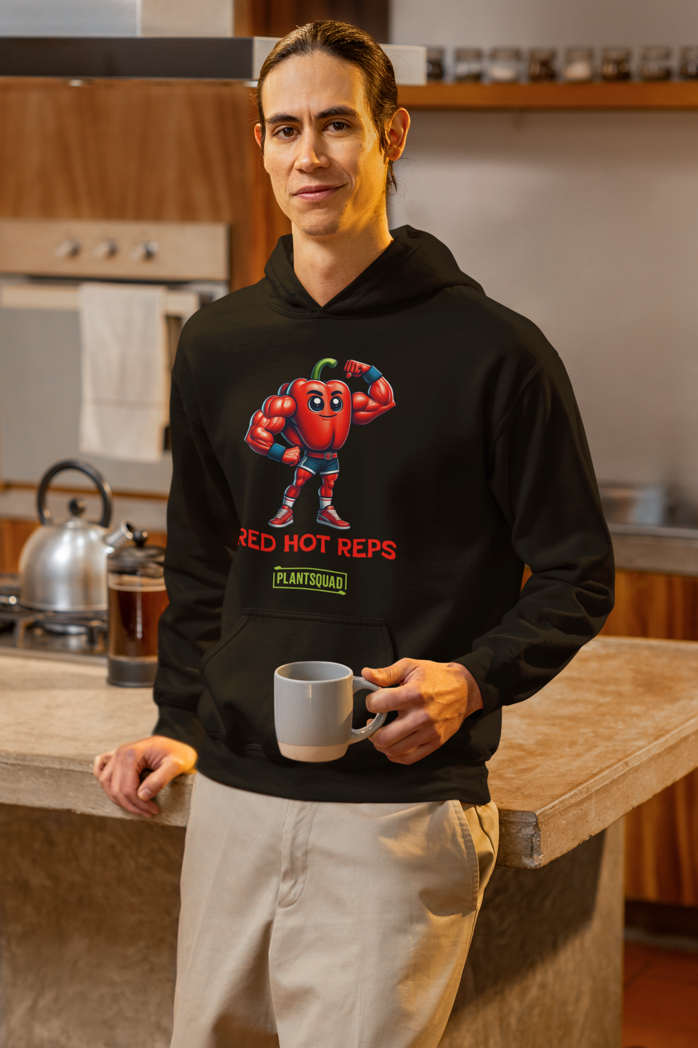 The Plantsquad Capsicum "Red Hot Reps" - Unisex Hoodie features a cartoon muscular red bell pepper character flexing its arms. The text "RED HOT REPS" is printed in red below the character, with "PLANTSQUAD" in green beneath it. Perfect workout clothing, the hoodie has a front pocket and drawstrings at the neck.