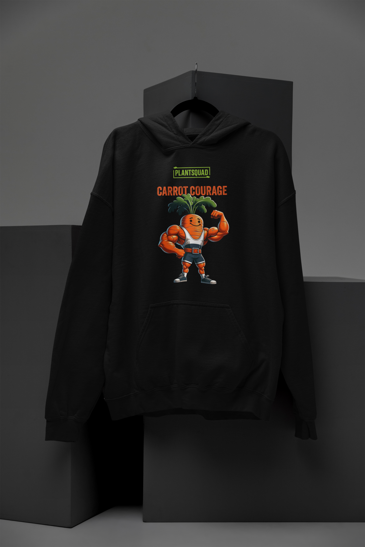 A Plantsquad Carrot "Carrot Courage" - Unisex Hoodie featuring a cartoon image of a muscular carrot character with green leafy hair, flexing its arms. Above the carrot, the text reads "PLANTSQUAD" and "CARROT COURAGE" in bold letters, perfect for those embracing the vegan lifestyle.