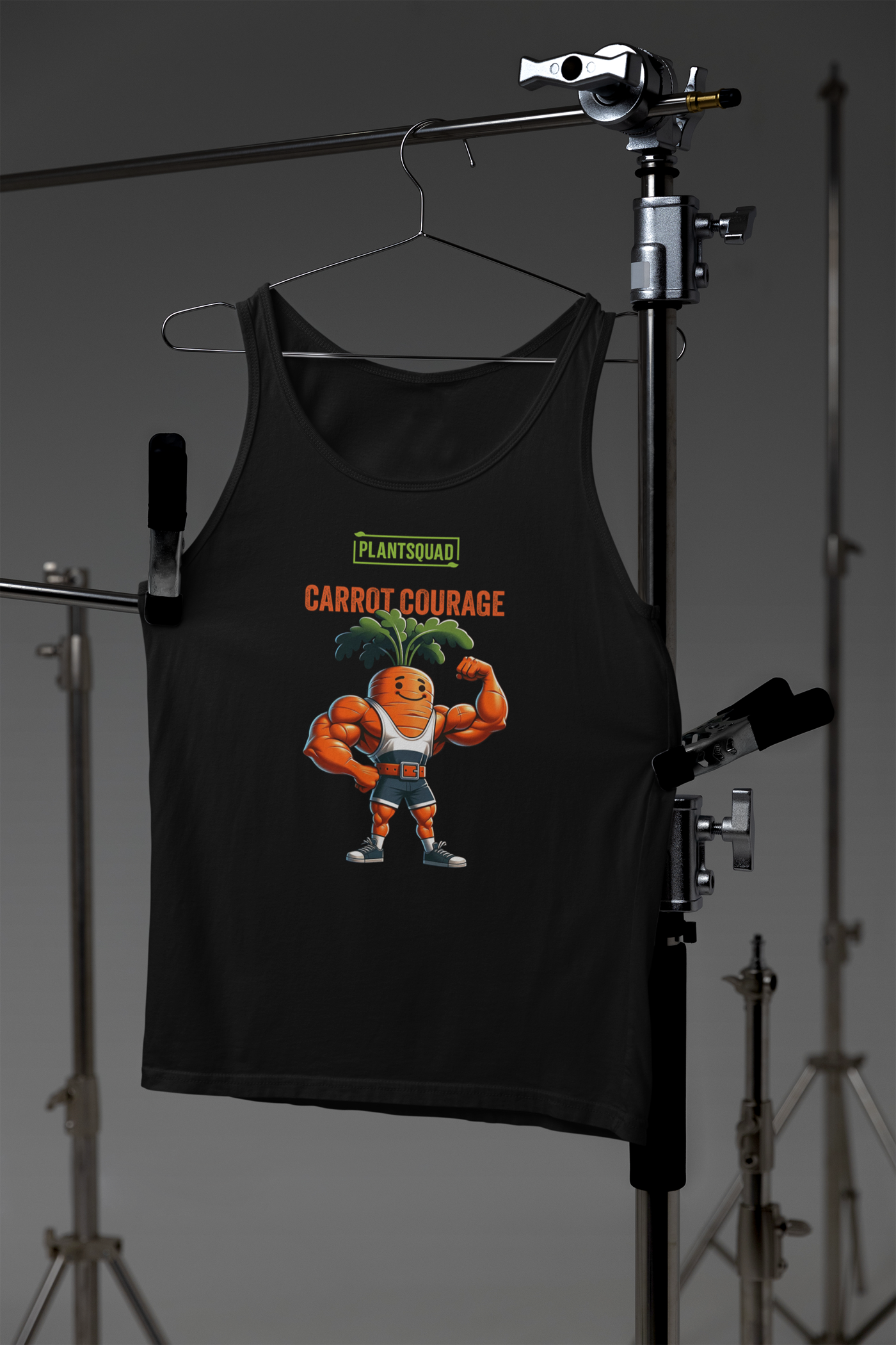 A black tank top featuring a muscular cartoon carrot with leafy green hair flexing its biceps. Above the carrot, “PLANTSQUAD” is written in green text, and below, “CARROT COURAGE” is in orange text. Perfect for gym enthusiasts embracing a vegan lifestyle, it's made from breathable fabric for maximum comfort. Introducing the Plantsquad Carrot "Carrot Courage" - Unisex Tank Top.