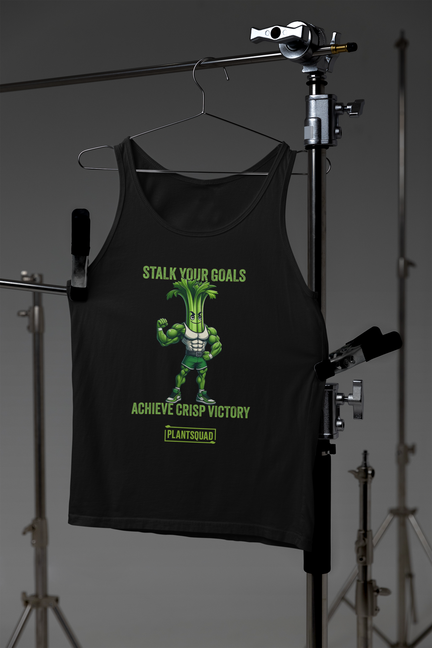 A Plantsquad Celery "Stalk Your Goals Achieve Crisp Victory" - Unisex Tank Top featuring an animated muscular celery character with a green body and determined expression. Above and below the character are the phrases, "Stalk Your Goals" and "Achieve Crisp Victory," respectively, in green text. This premium workout tank top is perfect for those embracing a plant-based lifestyle. A "PlantSquad" logo is at the bottom.