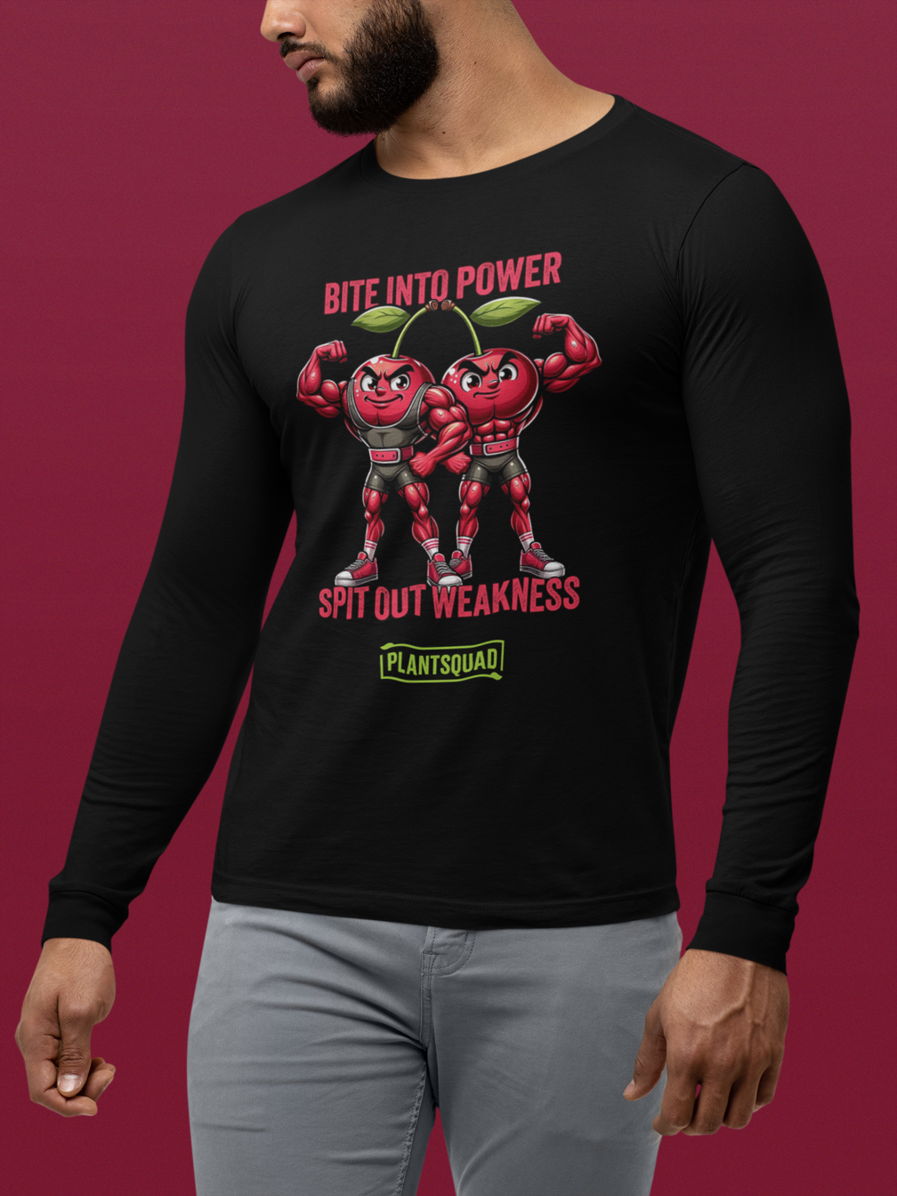 A Plantsquad Cherries "Bite Into Power Spit Out Weakness" - Unisex Long Sleeve T-Shirt featuring two muscular, anthropomorphic cherries flexing their arms. The text reads "Bite into Power, Spit out Weakness" above the muscly cherries cartoon, and "Plant Squad" below them, perfect for showcasing your commitment to a plant-based lifestyle.