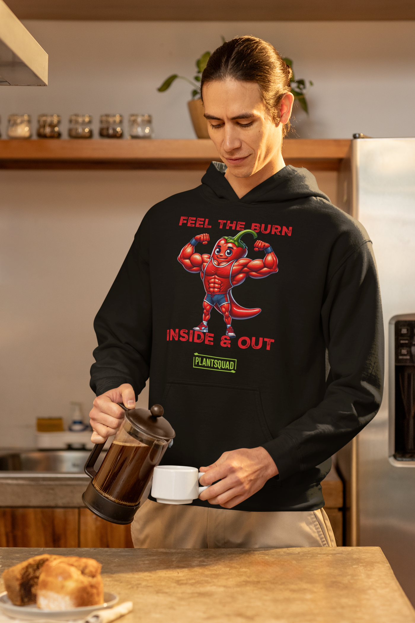 The Plantsquad Chilli "Feel The Burn Inside & Out" - Unisex Hoodie is a black weight lifting hoodie with a design of a muscular cartoon chili pepper flexing its muscles. The text above reads "Feel the Burn" and below it reads "Inside & Out." The bottom text features the logo "PlantSquad" in green and white, perfect for showcasing your plant-based, vegan lifestyle.