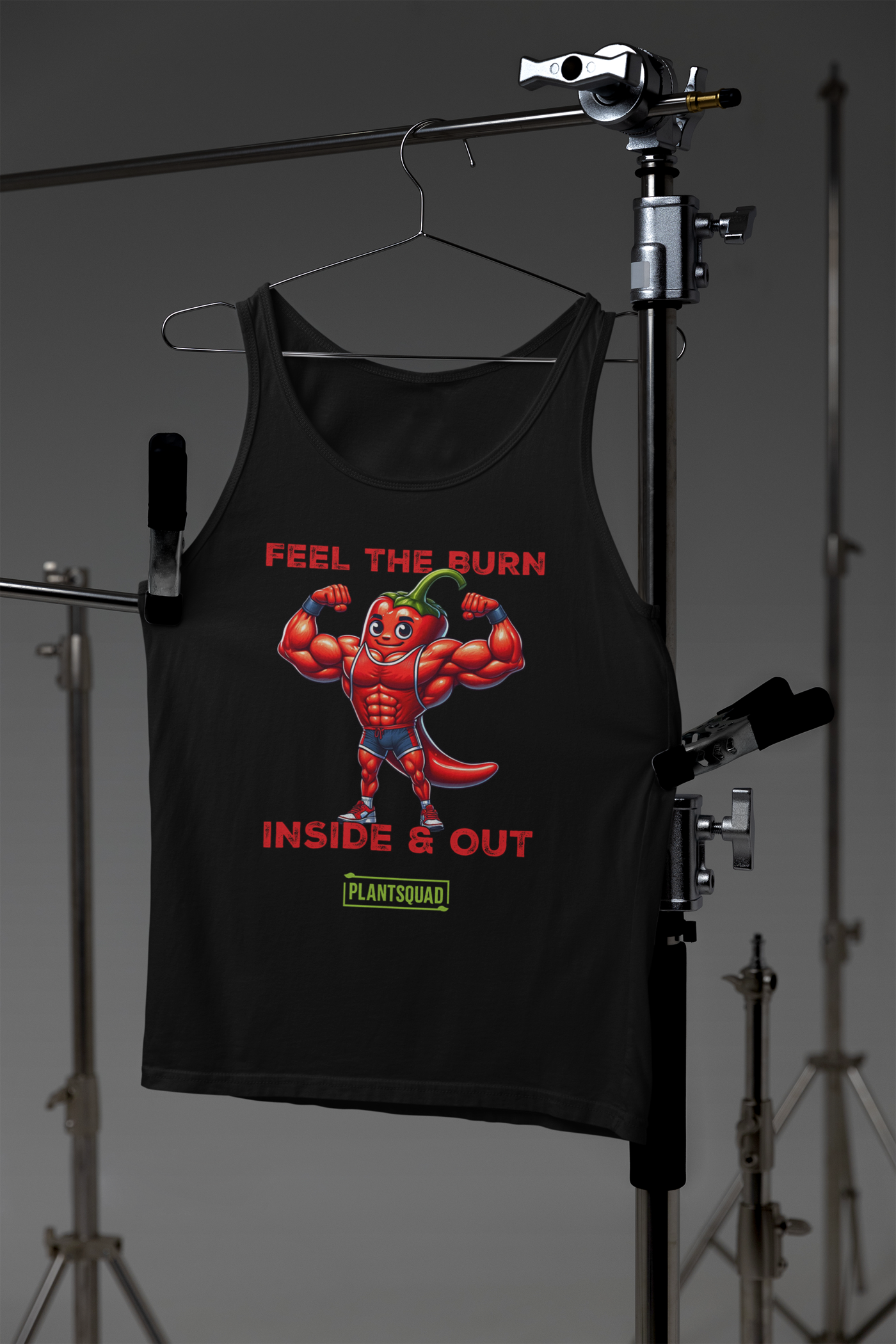 A black vegan tank top featuring a cartoon image of a muscular chili pepper flexing its biceps. The text above the image reads "FEEL THE BURN," and below it, "INSIDE & OUT." Crafted from premium breathable fabric, this Plantsquad Chilli "Feel The Burn Inside & Out" - Unisex Tank Top displays “PLANTSQUAD” at the bottom, perfect for showcasing your workout potential.