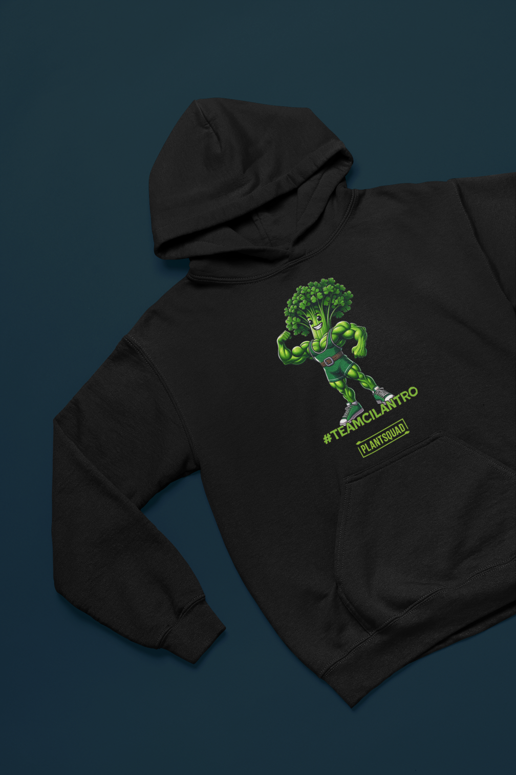 The Plantsquad Cilantro "Team Cilantro" - Unisex Hoodie features a cartoon of a muscular, flexing cilantro superhero, perfect for those embracing a vegan lifestyle. The character has a leafy head, an eye mask, and a belt. Below the character, the text reads "#TEAMCILANTRO" and "PLANTSQUAD.