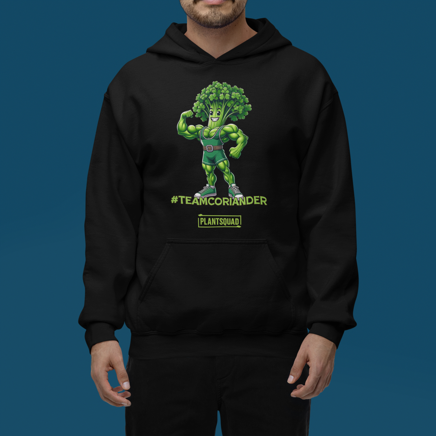 The Plantsquad Coriander "Team Coriander" - Unisex Hoodie features a cartoon illustration of a muscular green stalk of coriander wearing a superhero outfit, flexing its right arm. Embracing the vegan lifestyle, below it are the words "#TEAMCORIANDER" and "PLANTSQUAD" in bold, green text.