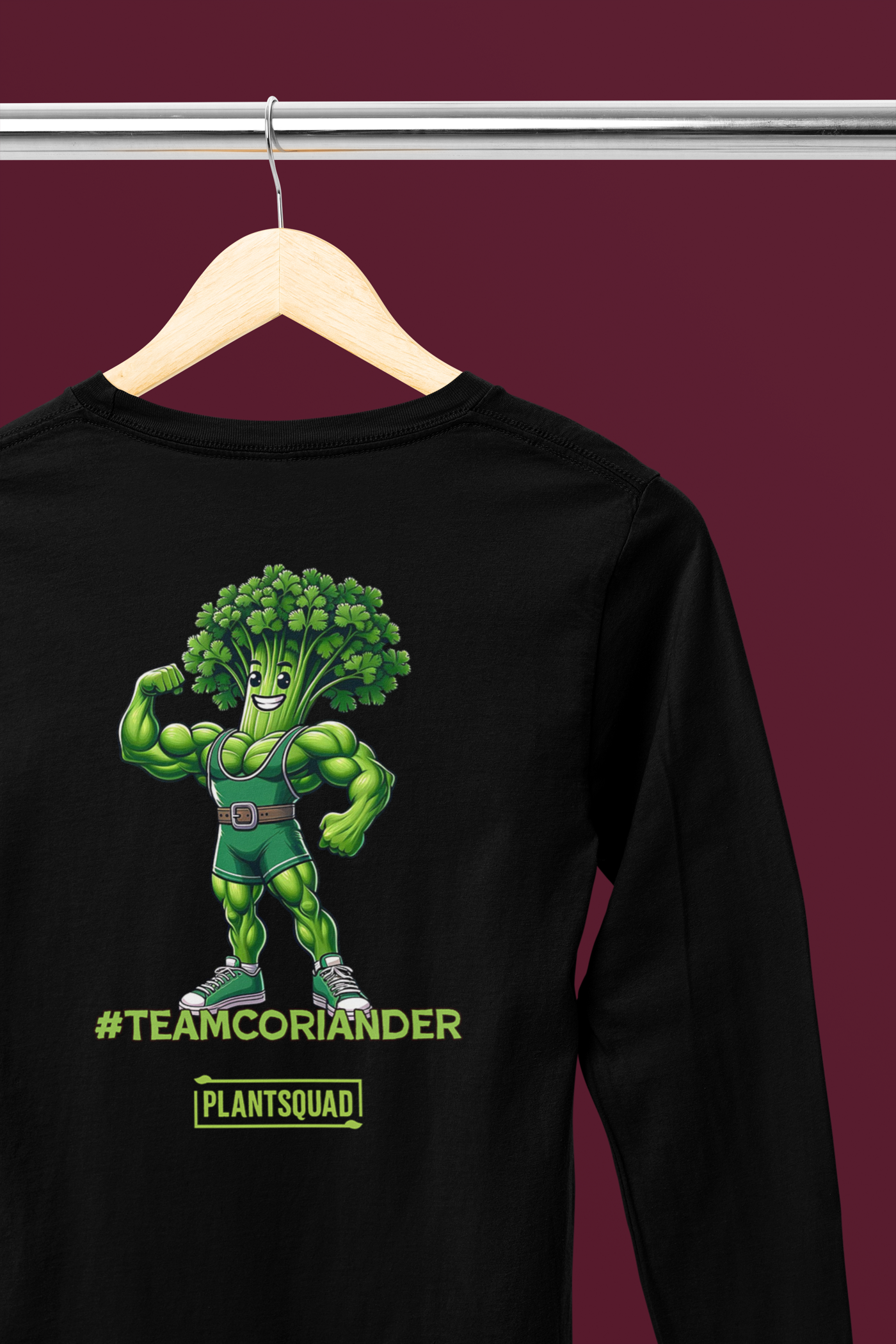 A Plantsquad Coriander "Team Coriander" - Unisex Long Sleeve T-Shirt featuring a muscly coriander cartoon character with a bodybuilder physique and a head of coriander leaves. The text "#TEAMCORIANDER" is displayed below the character, along with the logo "PLANTSQUAD" underneath. Perfect for fitness enthusiasts embracing a vegan lifestyle.