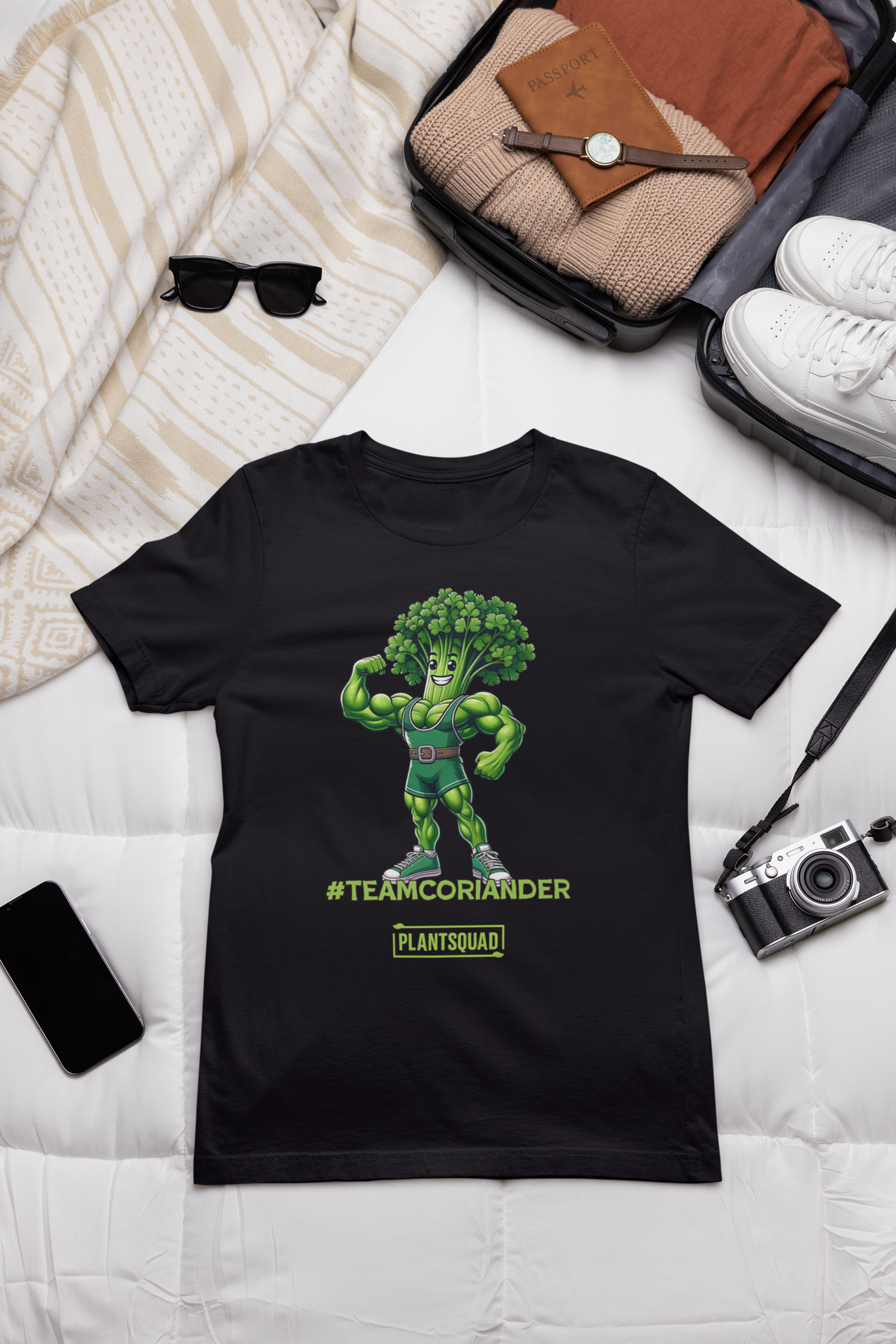 A black t-shirt featuring a cartoon anthropomorphic broccoli character flexing its muscles. The character is wearing a green singlet and sneakers. Text underneath reads "#TEAMCORIANDER" and "PLANTSQUAD" in bright green and yellow lettering, proudly showcasing your plantsquad spirit. This is the Plantsquad Coriander "Team Coriander" - Unisex T-Shirt.