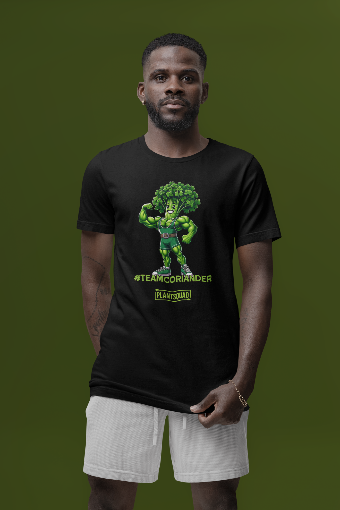 A black t-shirt featuring a cartoon anthropomorphic broccoli character flexing its muscles. The character is wearing a green singlet and sneakers. Text underneath reads "#TEAMCORIANDER" and "PLANTSQUAD" in bright green and yellow lettering, proudly showcasing your plantsquad spirit. This is the Plantsquad Coriander "Team Coriander" - Unisex T-Shirt.