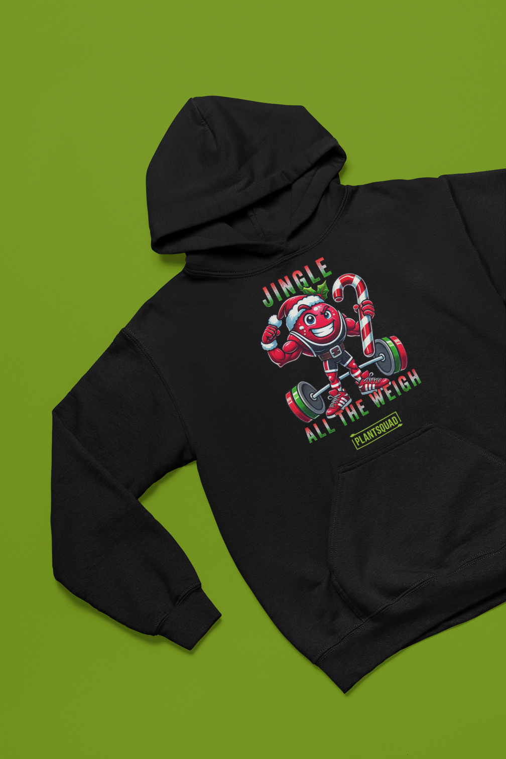 A picture of a hoodie featuring a strong looking cranberry cartoon character flexing its arms holding a candy cane.  A small green logo "PLANTSQUAD" appears above the character, "JINGLE ALL THE WEIGH" below. Perfect for those embracing a plant-based or vegan lifestyle that are into fitness