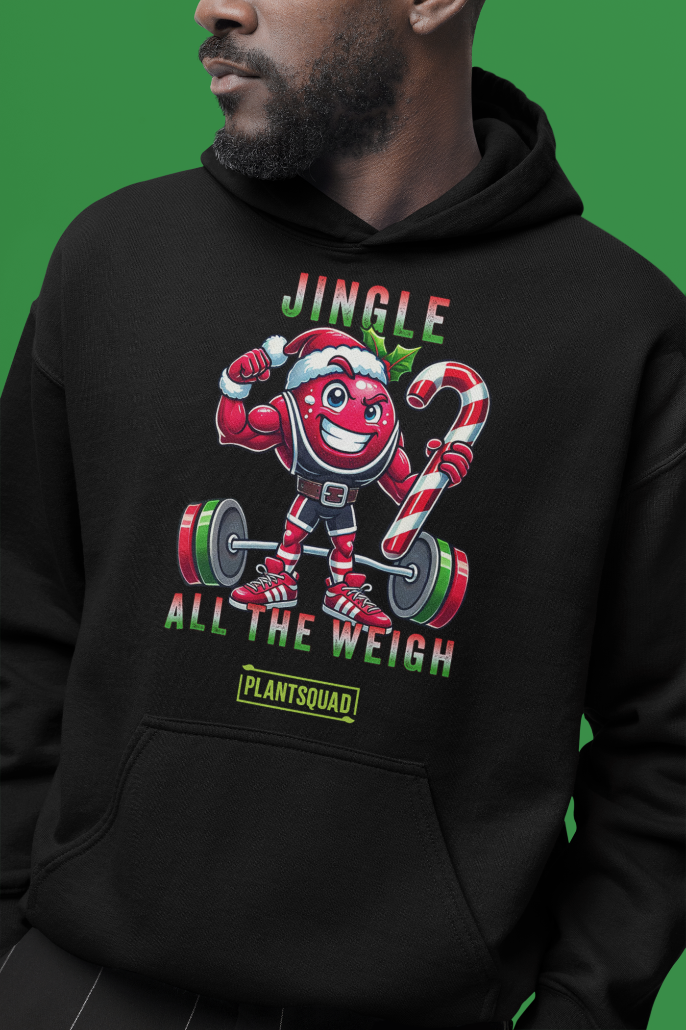 A model featuring a muscled cranberry cartoon character flexing its arms holding a candy cane.  A small green logo "PLANTSQUAD" appears above the character, "JINGLE ALL THE WEIGH" below. Perfect for those embracing a plant-based or vegan lifestyle that are into fitness