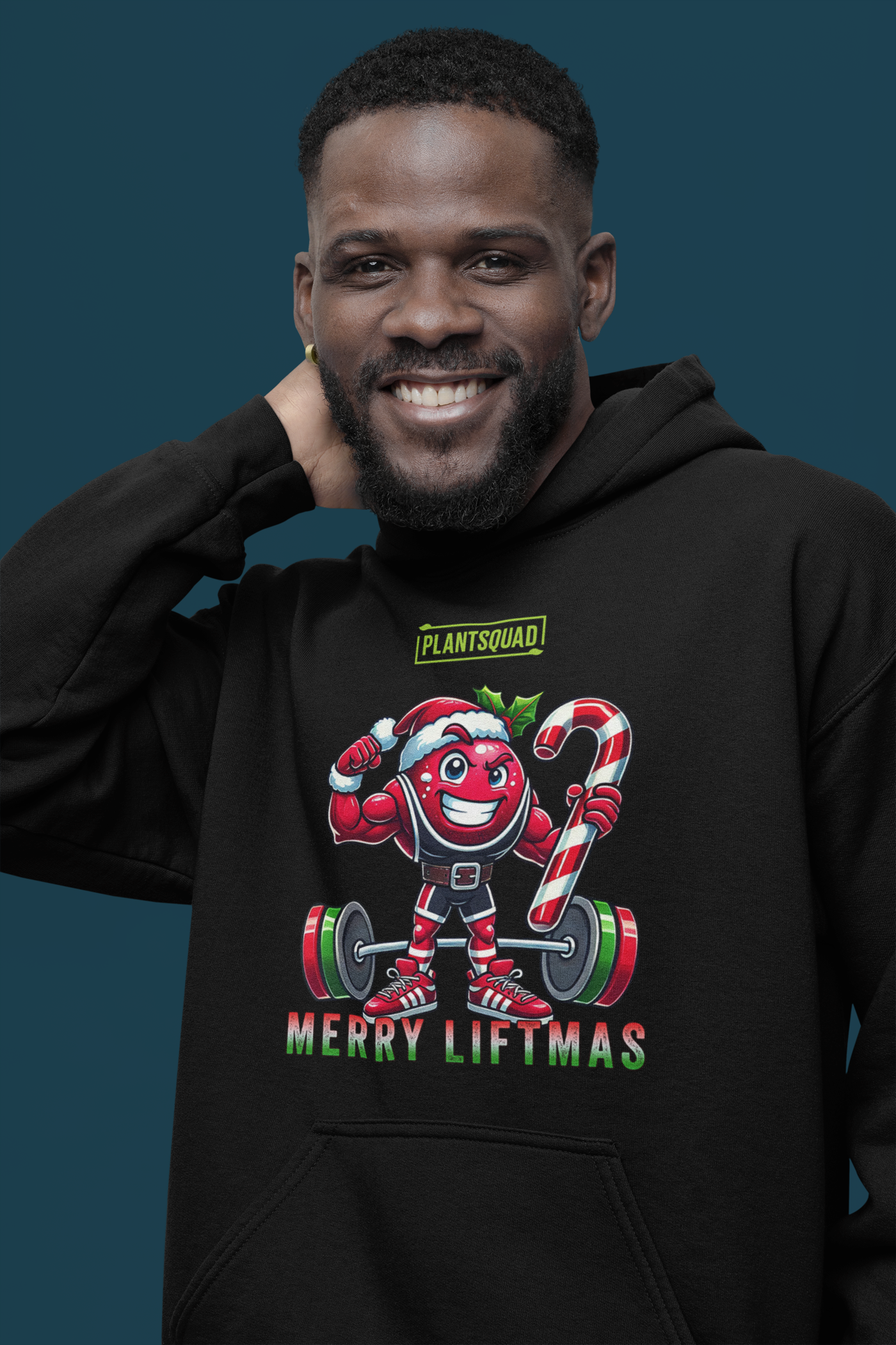 A model featuring a muscled cranberry cartoon character flexing its arms holding a candy cane.  A small green logo "PLANTSQUAD" appears above the character, "MERRY LIFTMAS" below. Perfect for those embracing a plant-based or vegan lifestyle that are into fitness