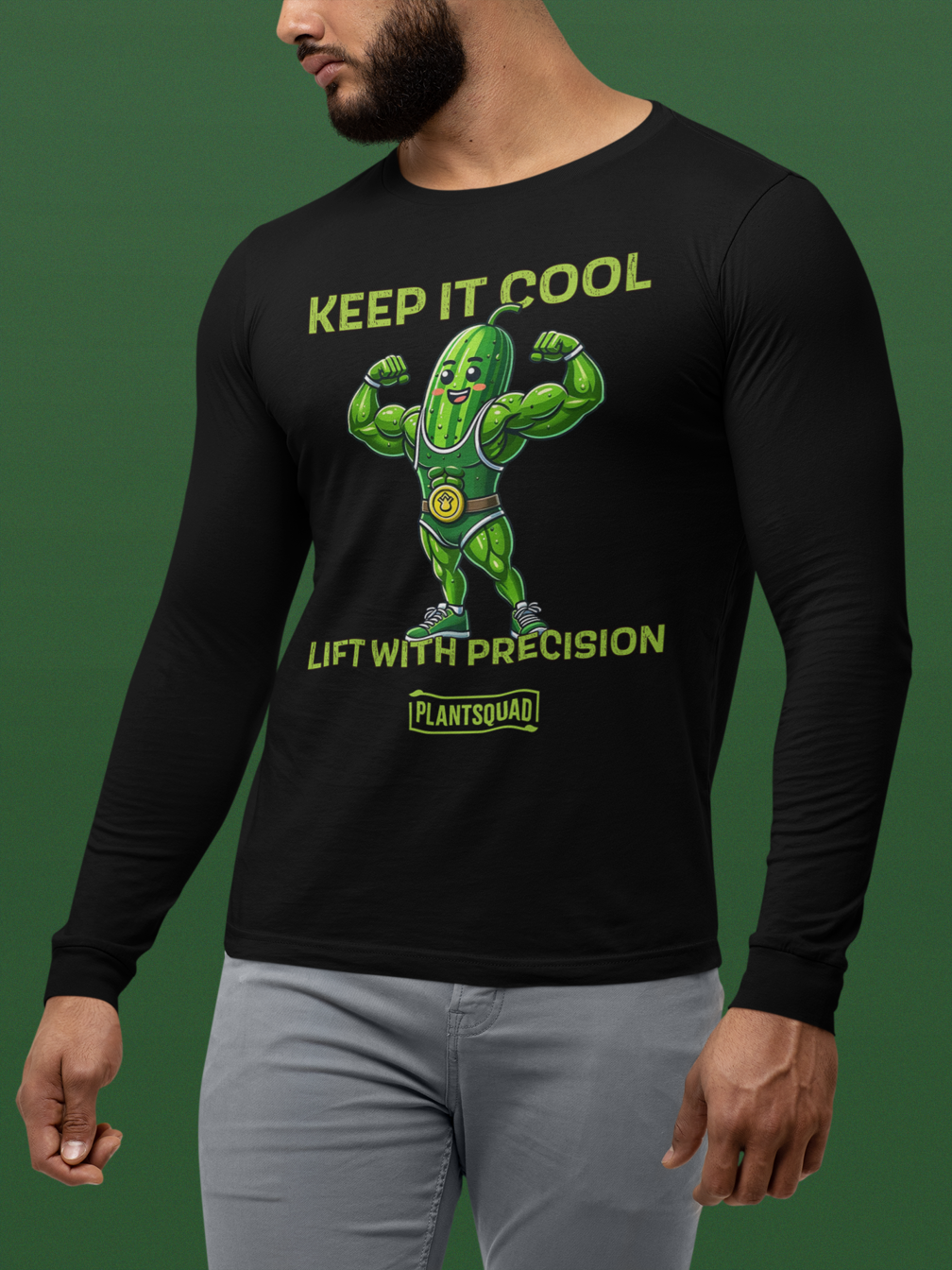 A Plantsquad Cucumber "Keep It Cool Lift With Precision" - Unisex Long Sleeve T-Shirt featuring a cartoon pickle character flexing muscular arms, wearing a green superhero-like costume. Above the pickle, text reads "KEEP IT COOL," and below, it says "LIFT WITH PRECISION." Ideal for those into vegan fitness and proudly part of the "PLANTSQUAD.